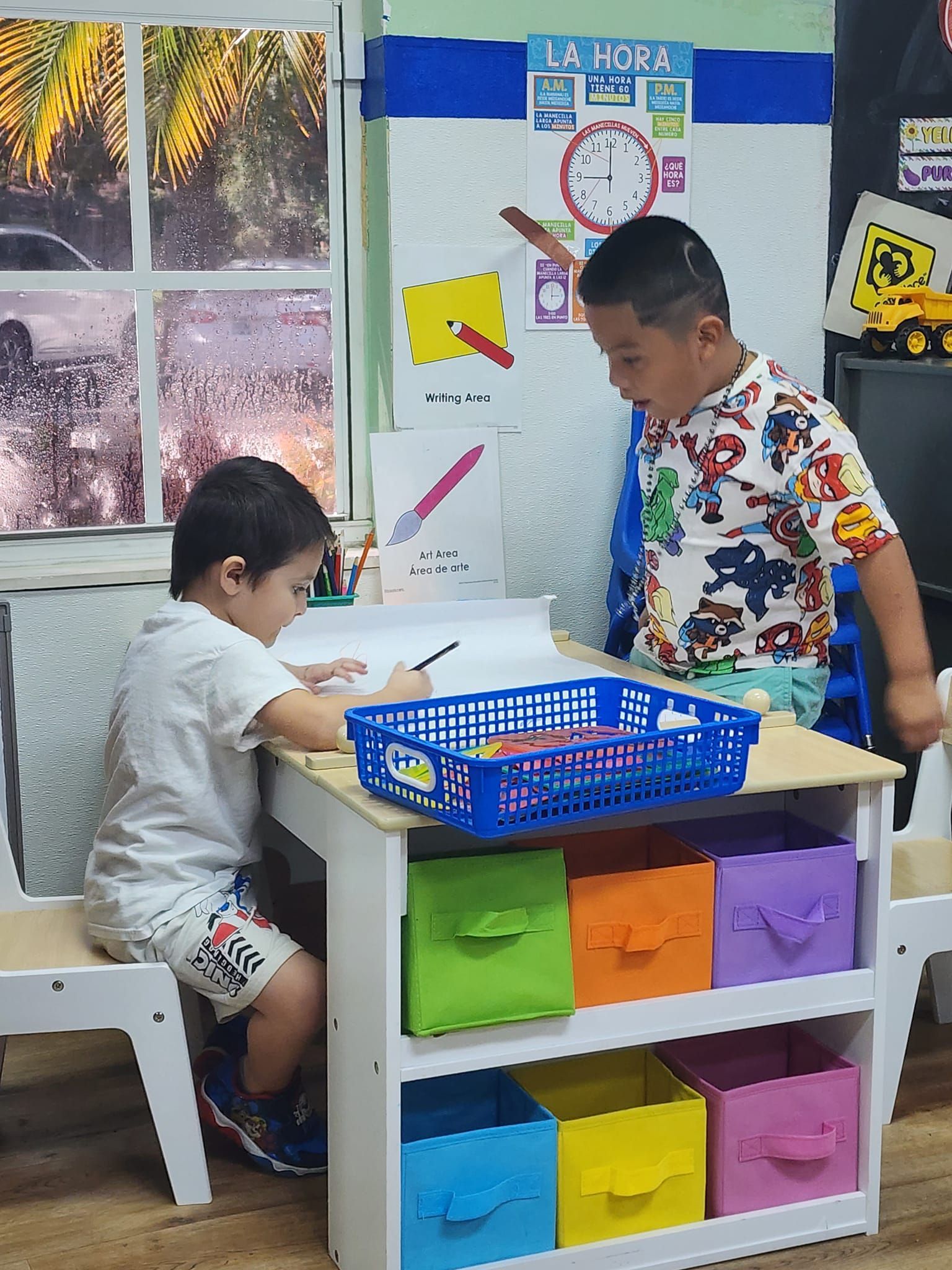 Two young boys are sitting at a table in a classroom.