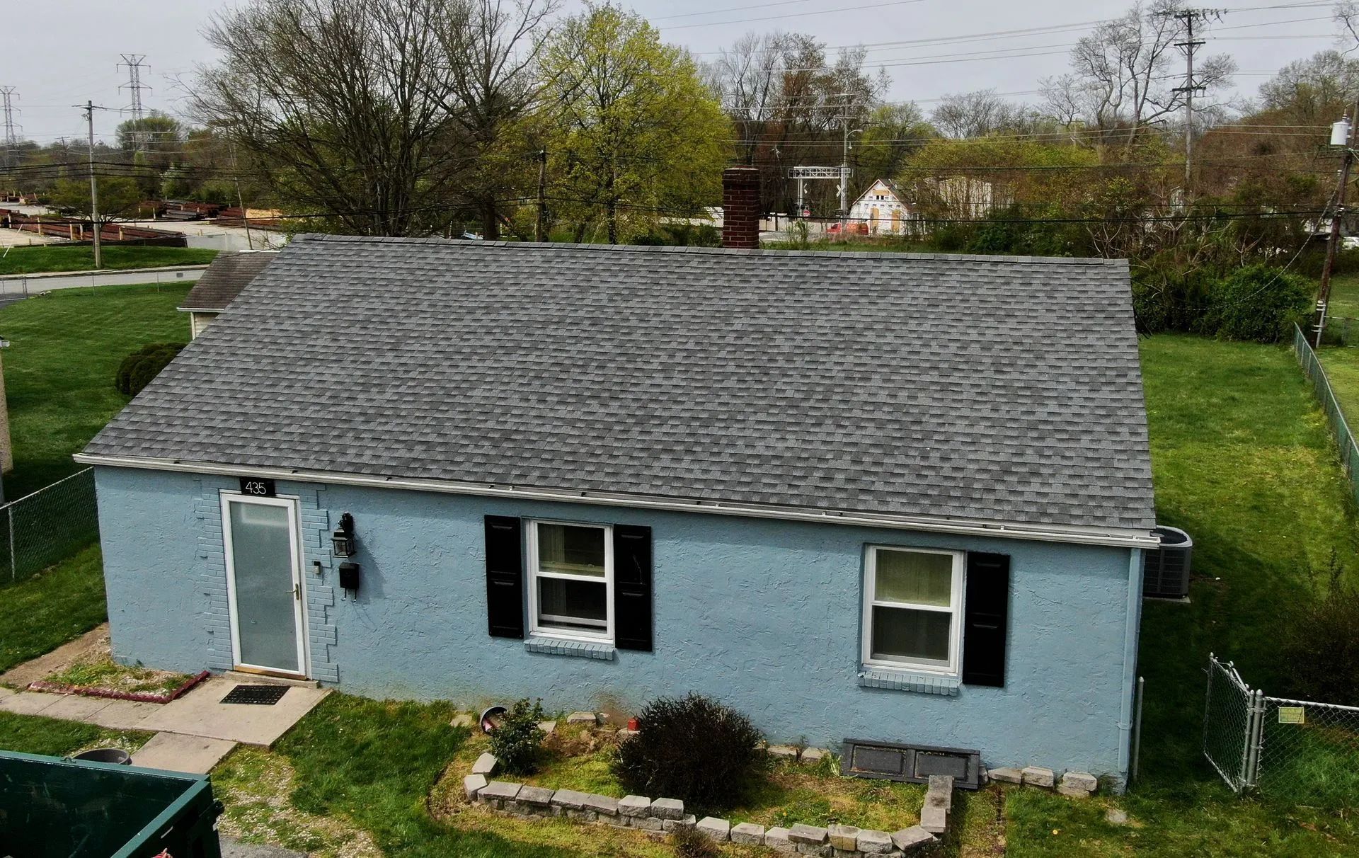 An aerial view of a blue house with a gray roof and black shutters.