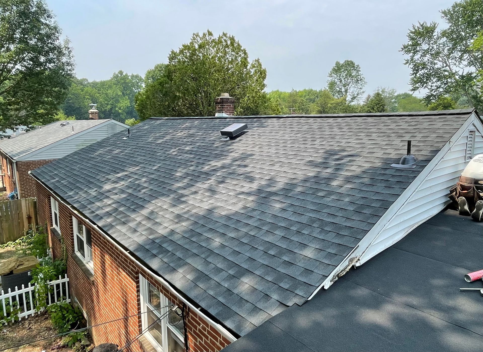 The roof of a brick house with a black shingle roof.