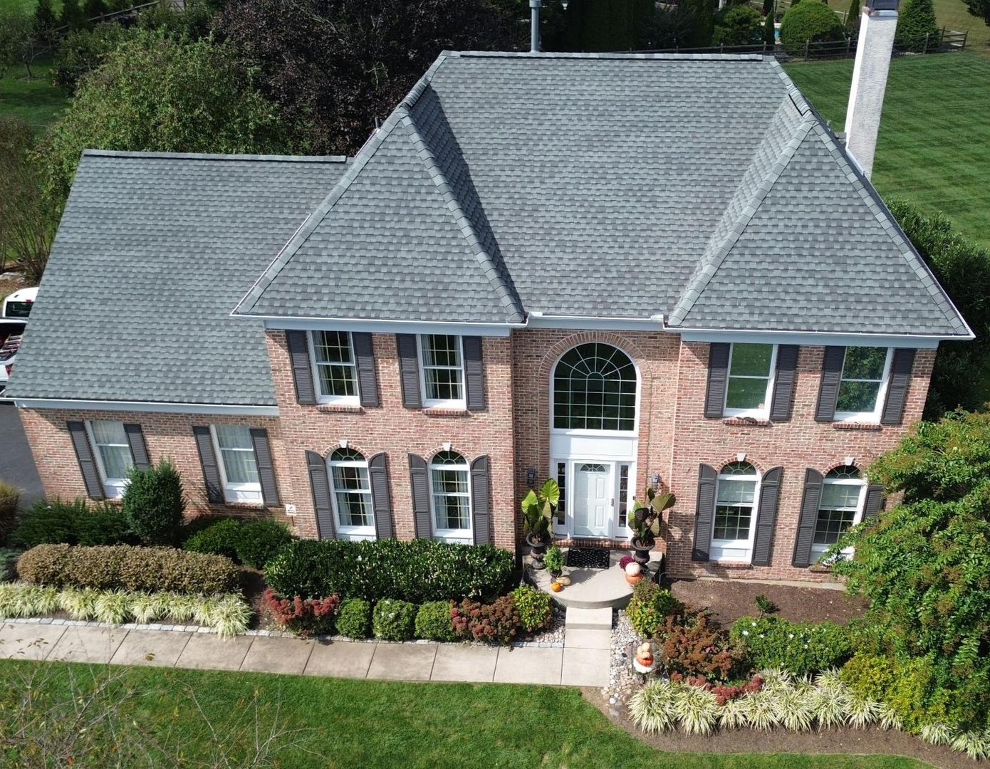 Brick house with gray roof, black shutters, and well-kept landscaping.