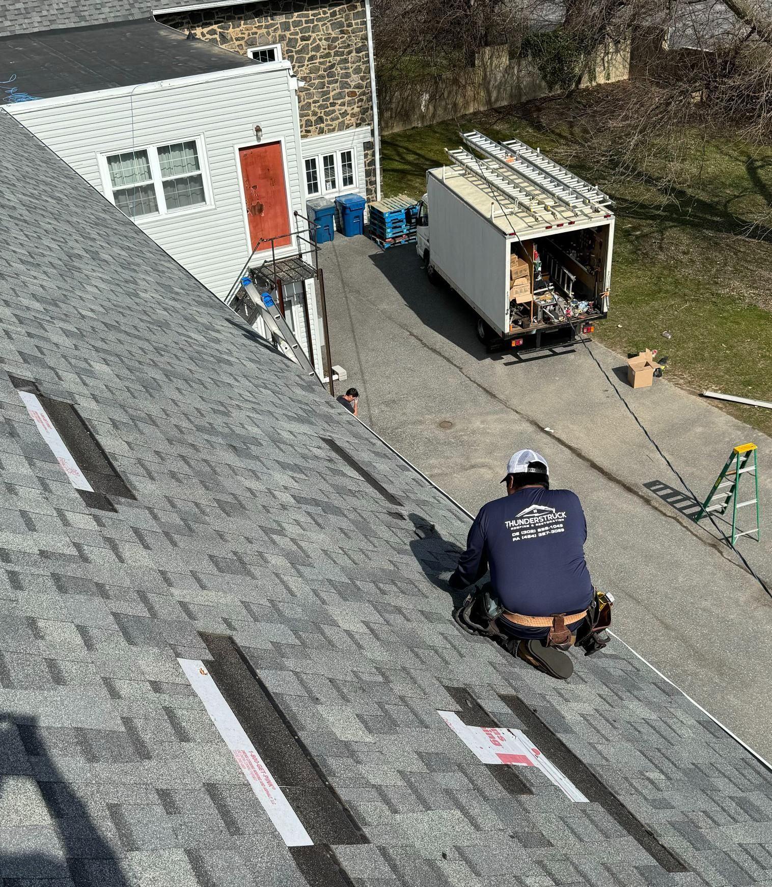 A man is kneeling on the roof of a house.