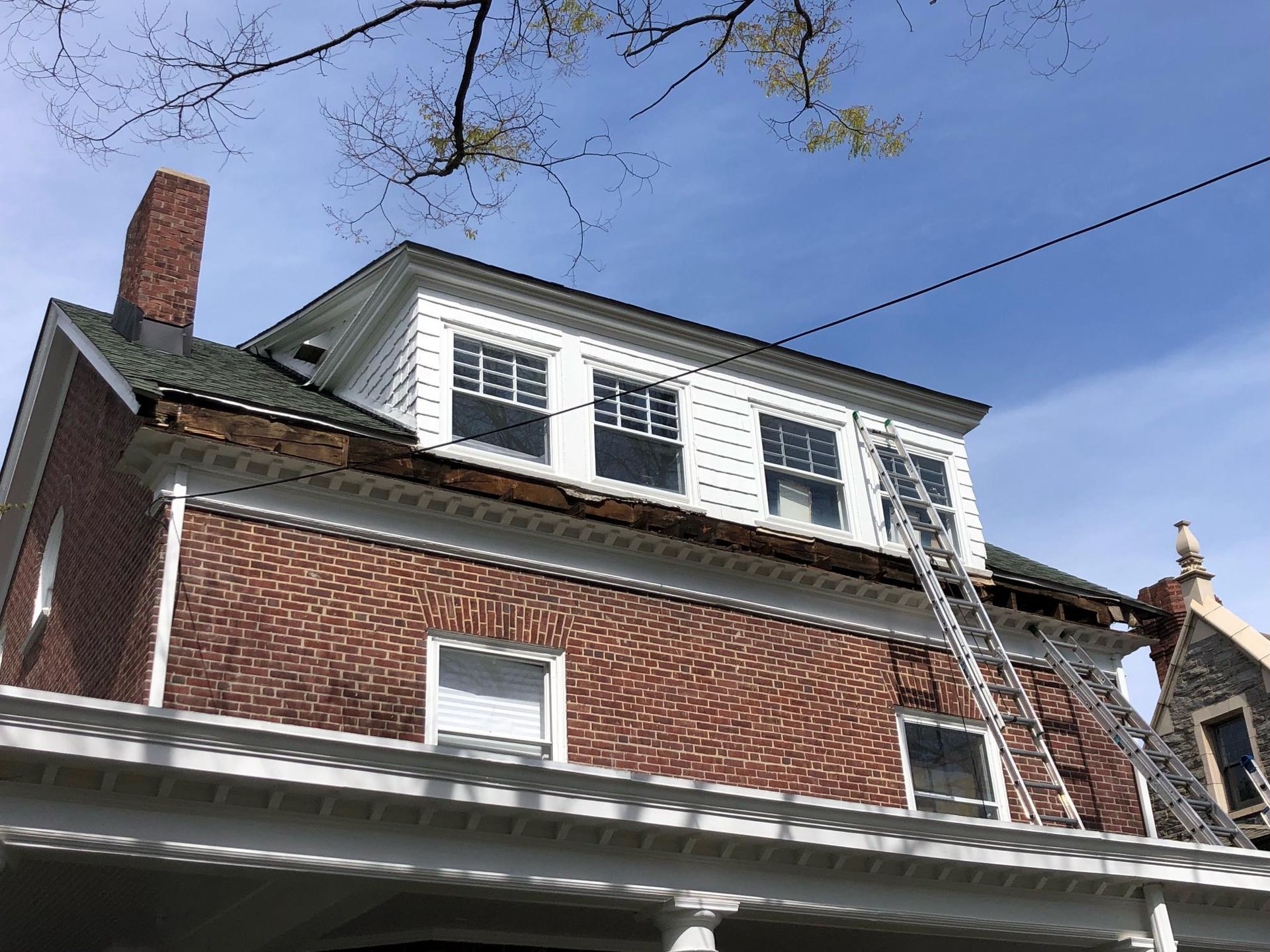 A brick house with a ladder on the roof.