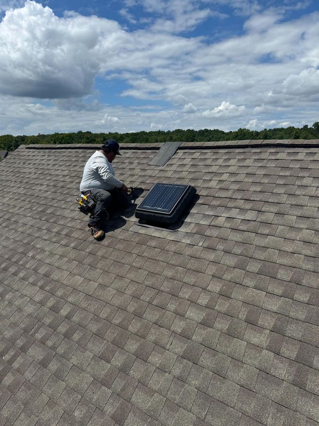 Two men are working on the roof of a house.