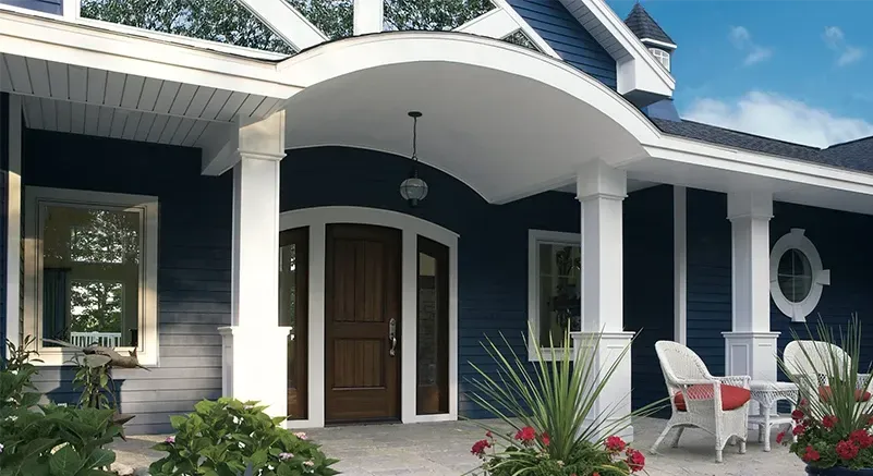 Aerial view of a gray house with a lawn, a street, and vehicles.