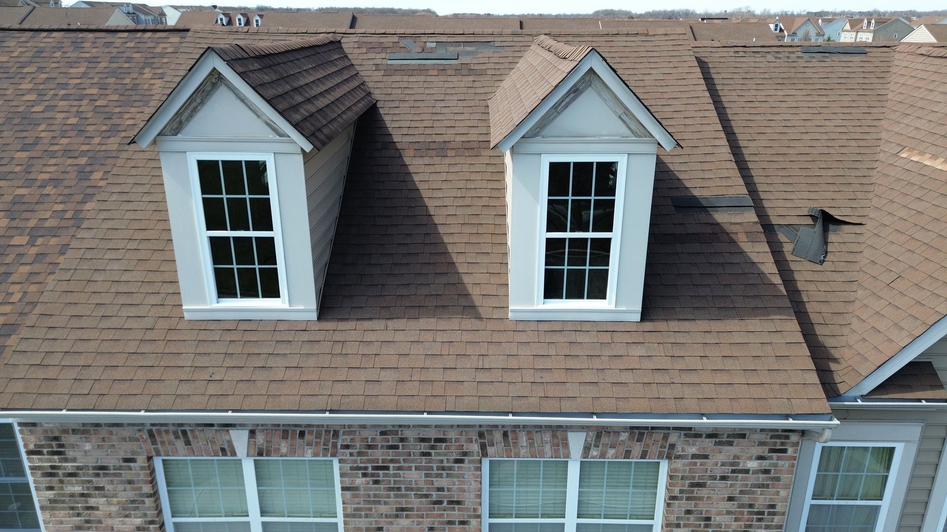 A man is sitting on the roof of a house.
