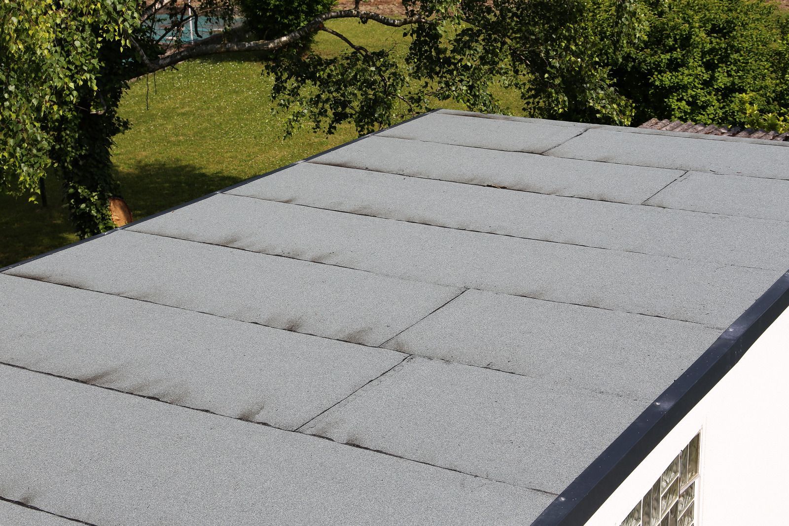 A close up of a roof with trees in the background