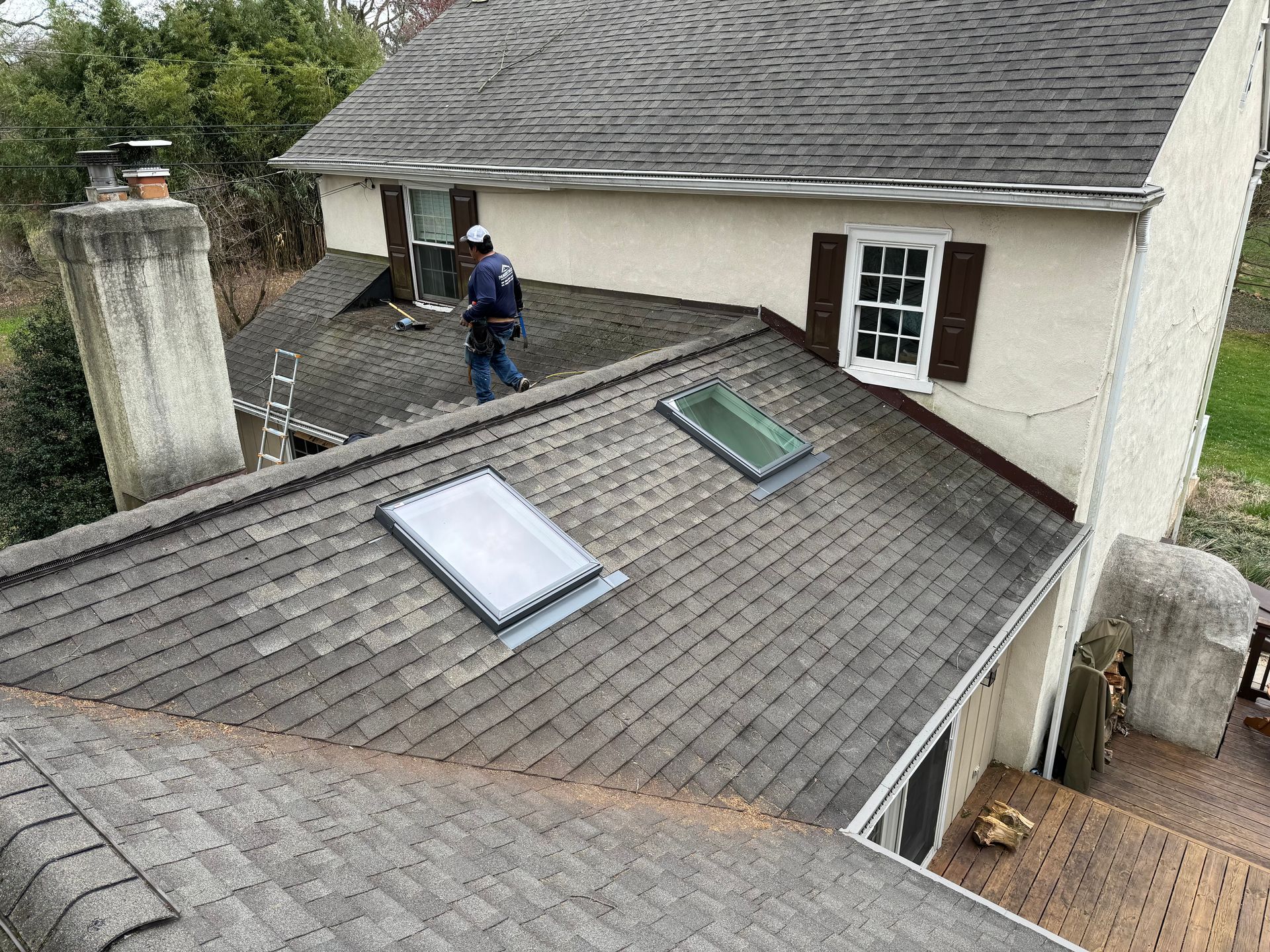 A house with a garage and a roof with trees in the background.