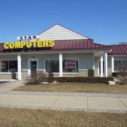 Star Computers storefront with yellow sign, gray building, and burgundy roof on a sunny day.