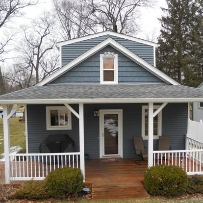 Blue-sided house with a porch, white trim, and a small gabled dormer.
