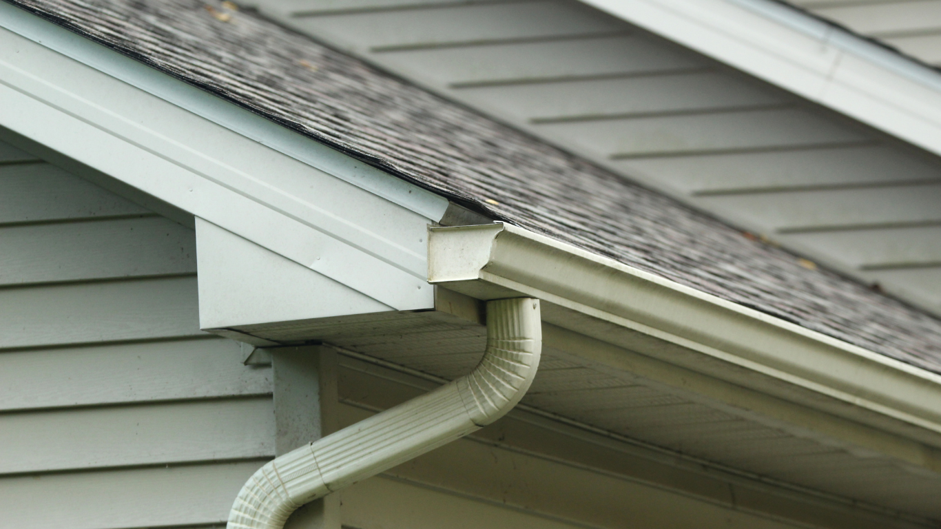 Light blue gutters and downspout on a house with gray siding and roof.