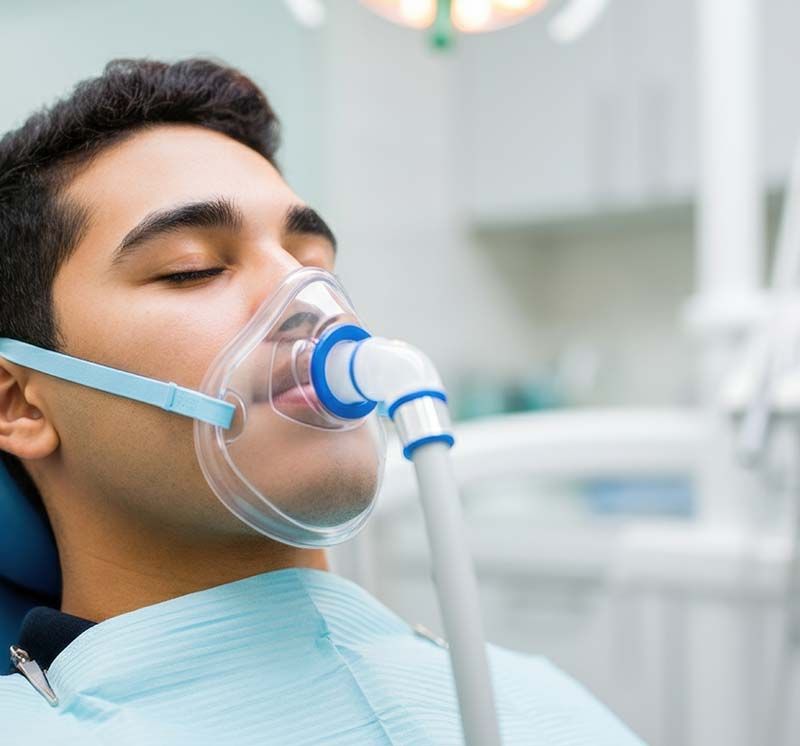 A person in a dental chair wearing a mask for nitrous oxide sedation.