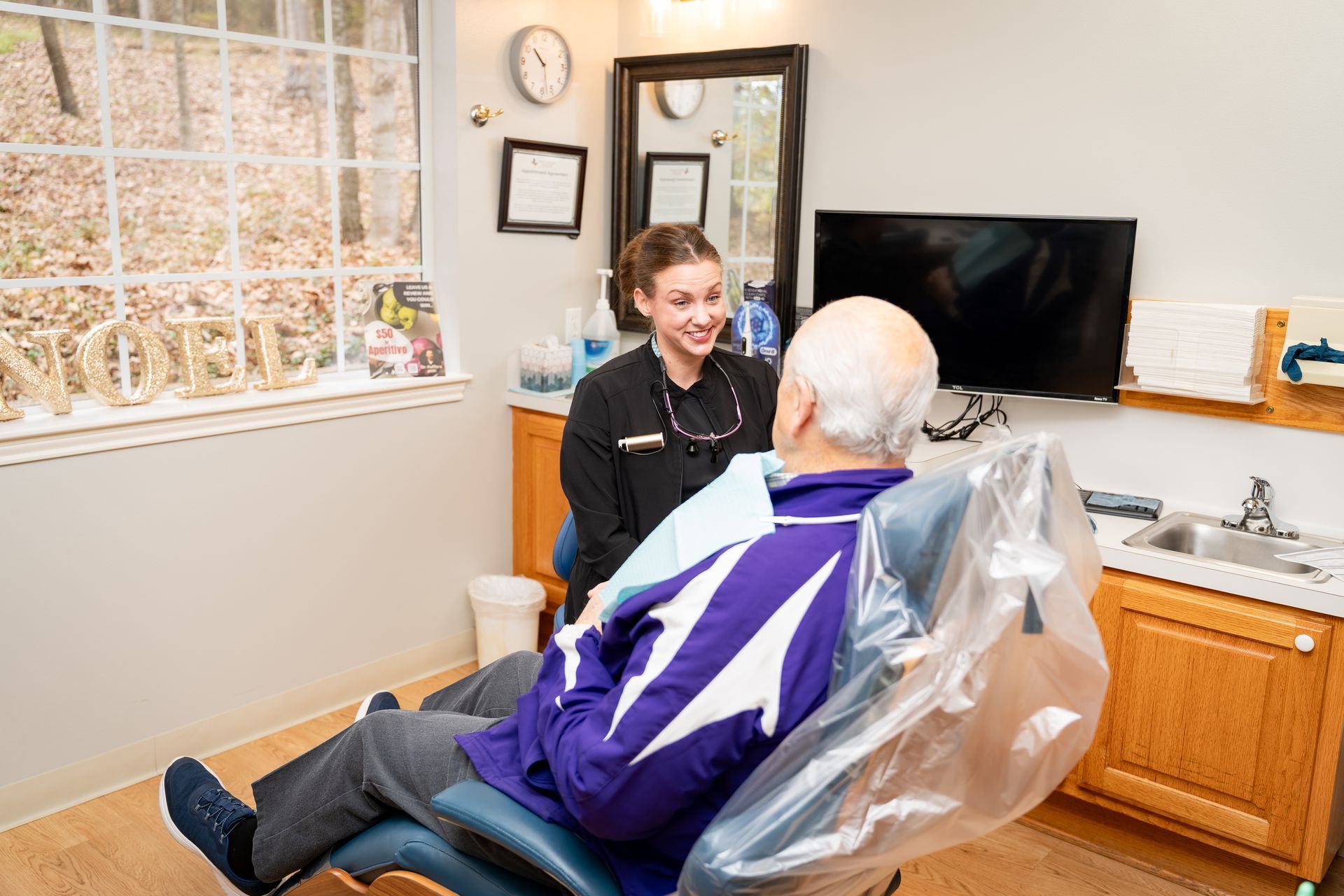 A professional conversing with a patient in a dental chair within a clinic office.