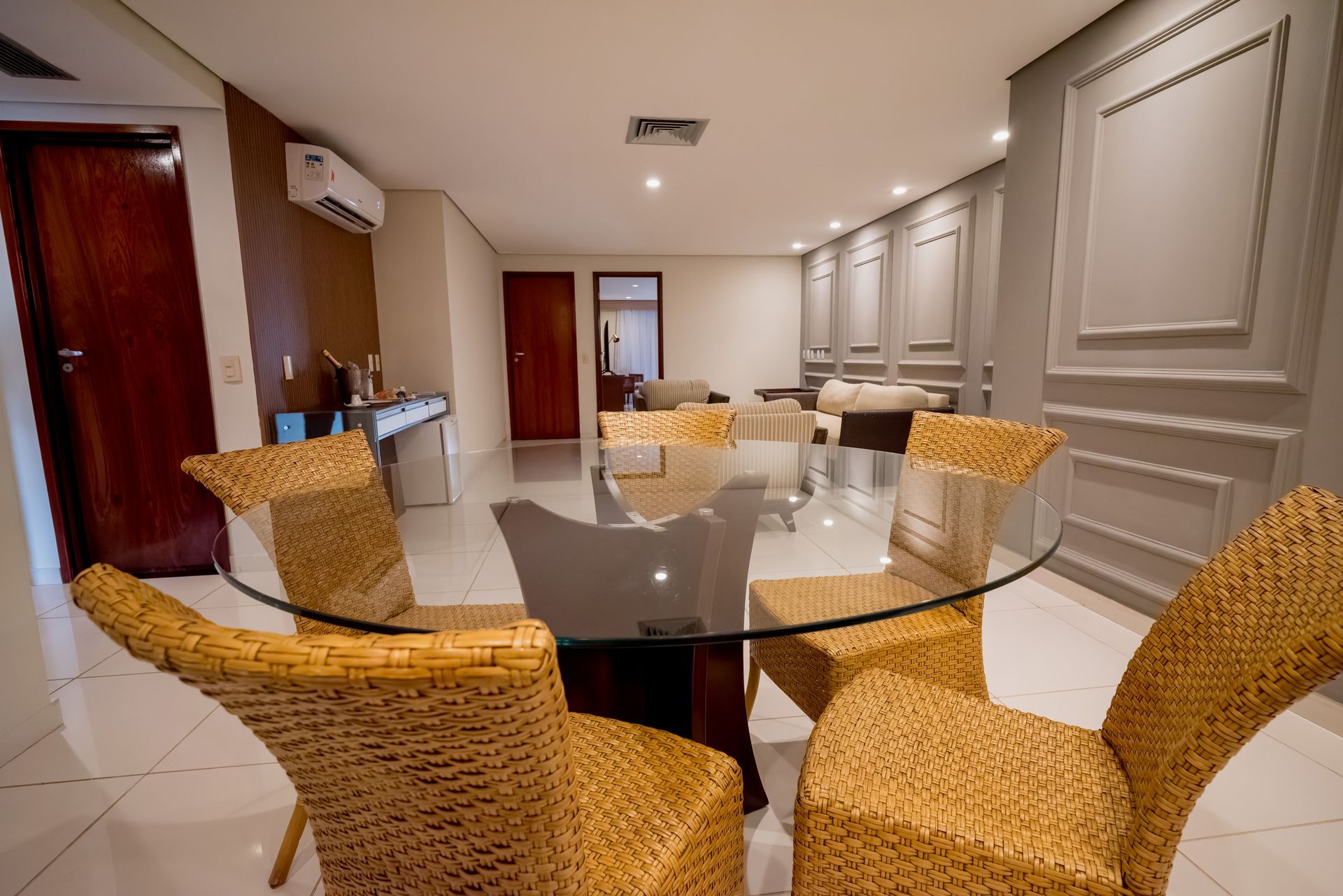 Uma sala de jantar com cadeiras de vime e uma mesa de vidro