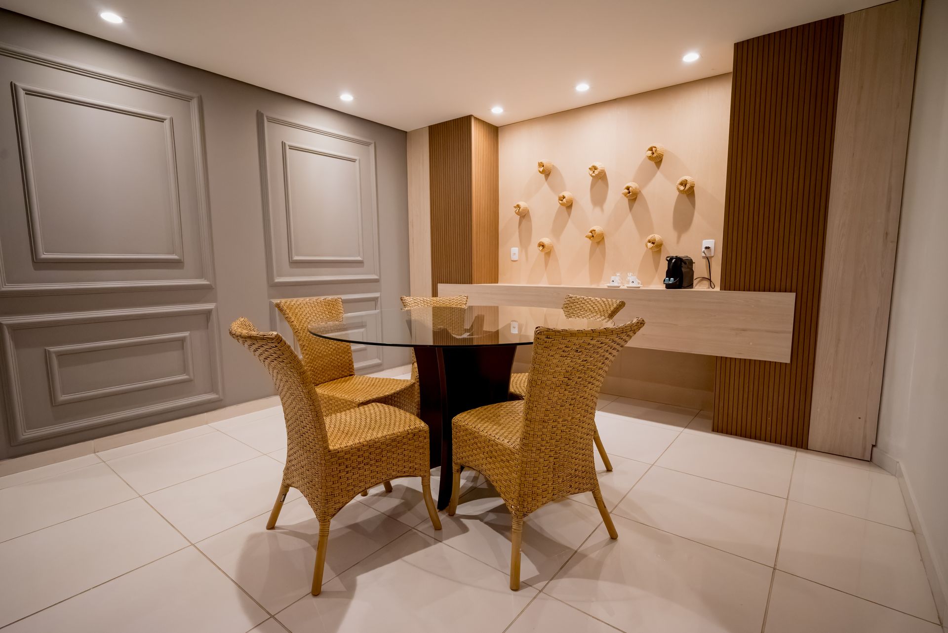 Uma sala de jantar com uma mesa de vidro e cadeiras de vime.