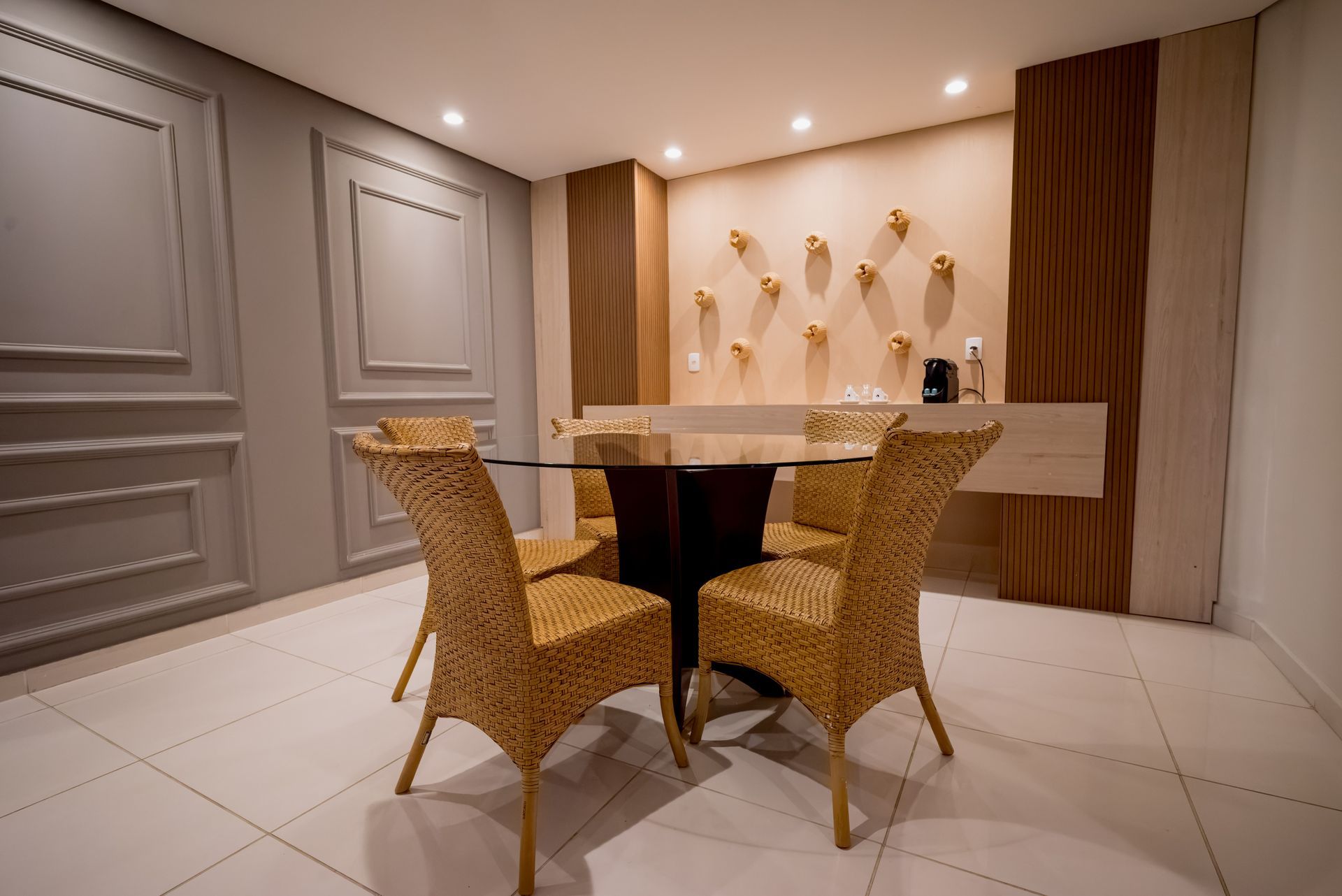 Uma sala de jantar com cadeiras de vime e uma mesa de vidro.