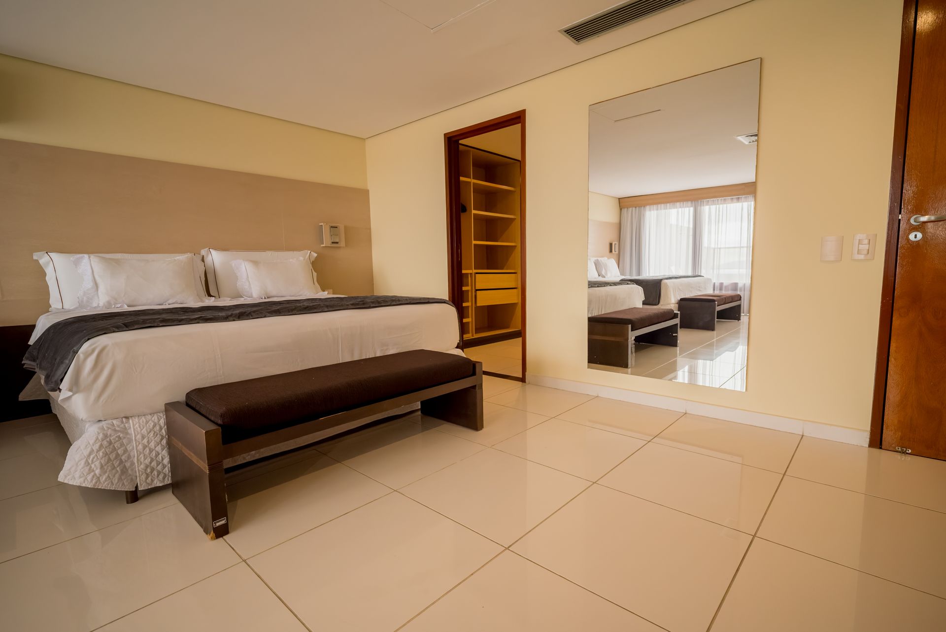 Um quarto de hotel com uma cama king size e um banco.