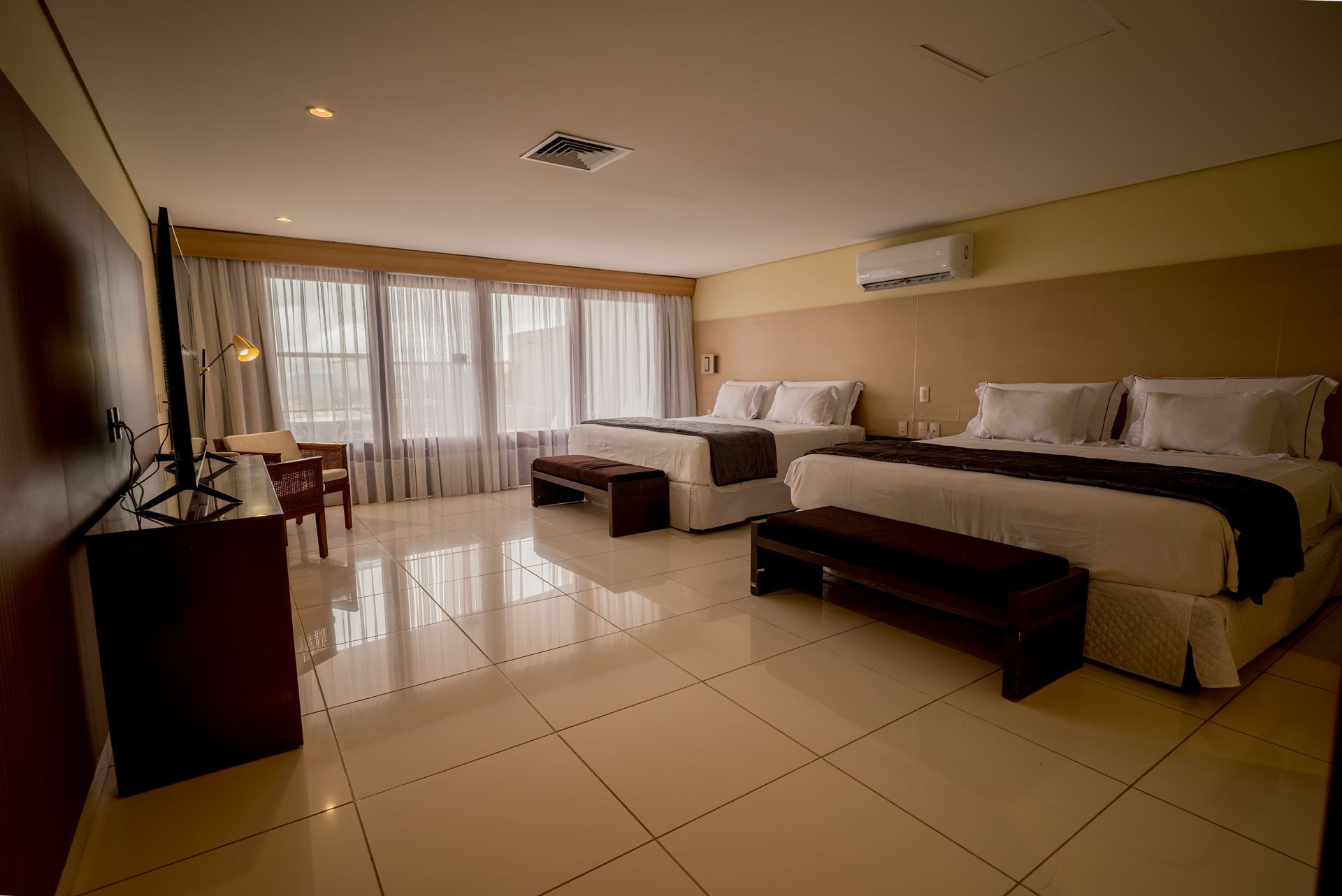 Um quarto de hotel com duas camas, uma escrivaninha e uma televisão.