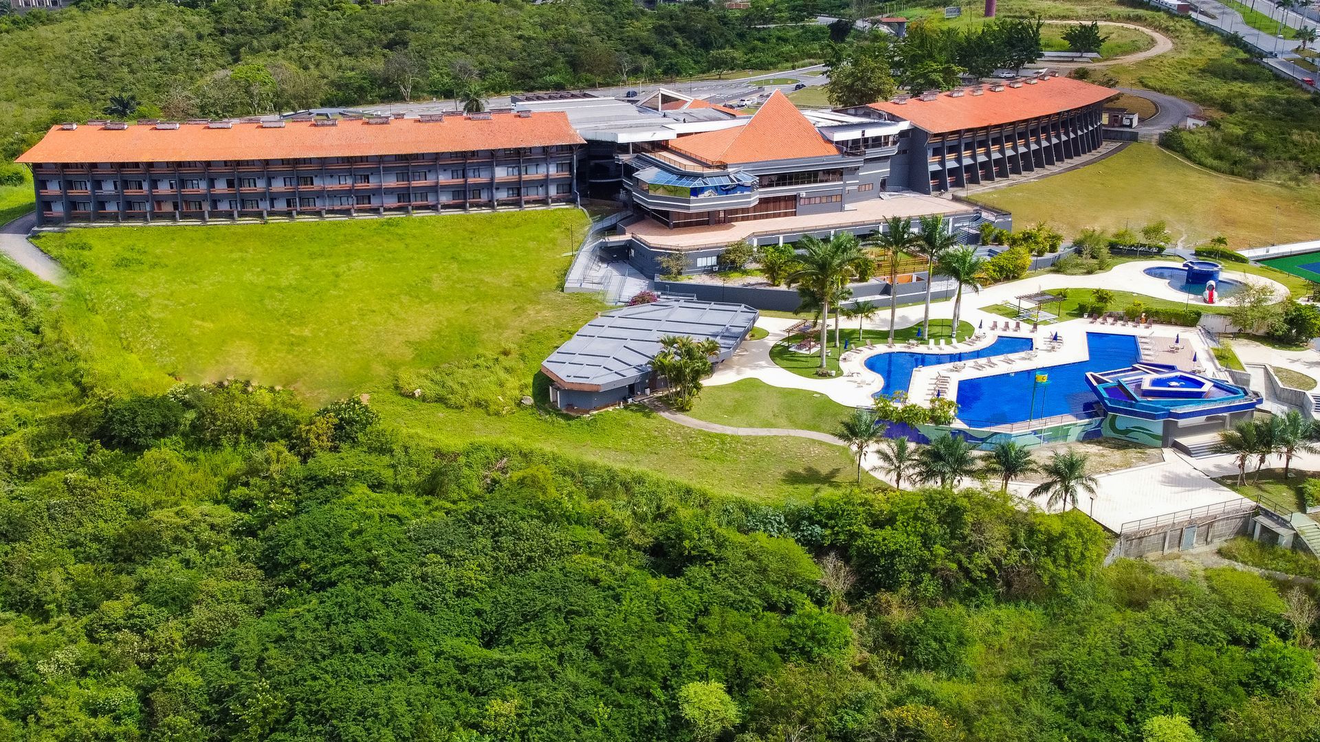 Uma vista aérea de um grande hotel cercado por árvores e uma piscina.