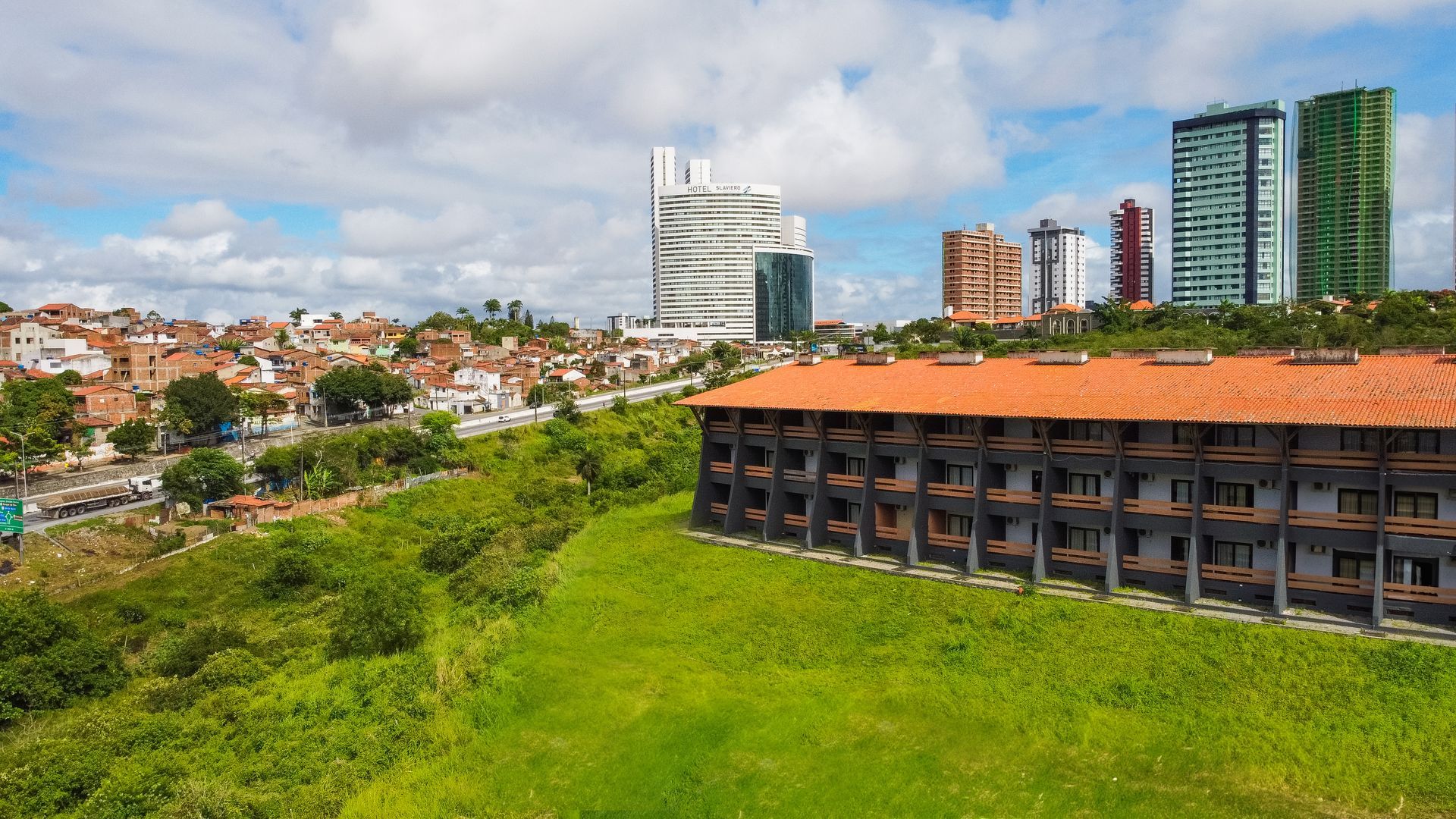 Uma vista aérea de um grande edifício com um telhado vermelho no meio de uma cidade.