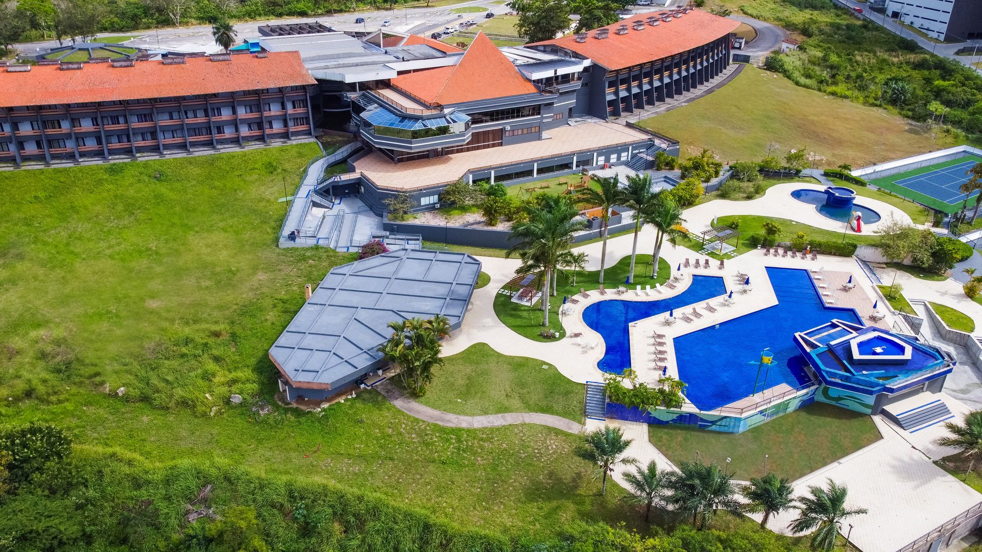 Uma vista aérea de um grande hotel com uma piscina cercada por palmeiras.
