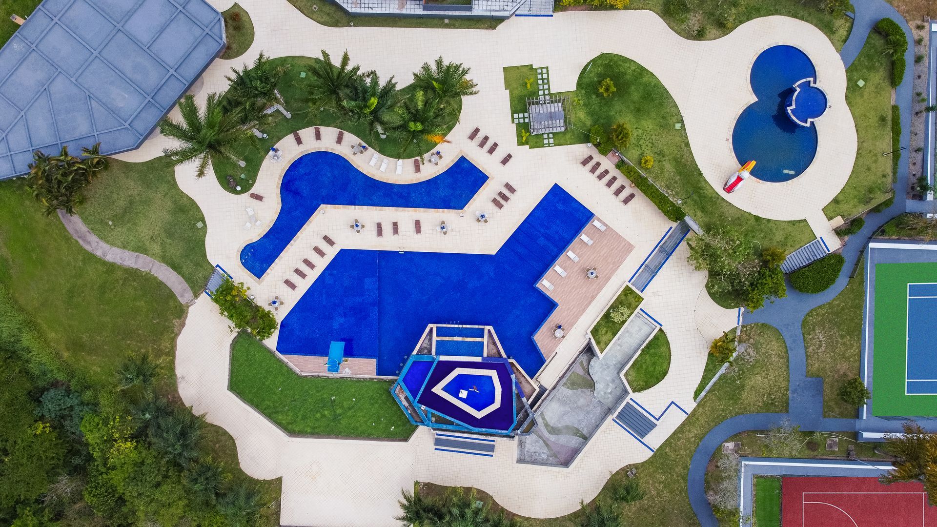 Uma vista aérea de uma piscina e quadras de tênis