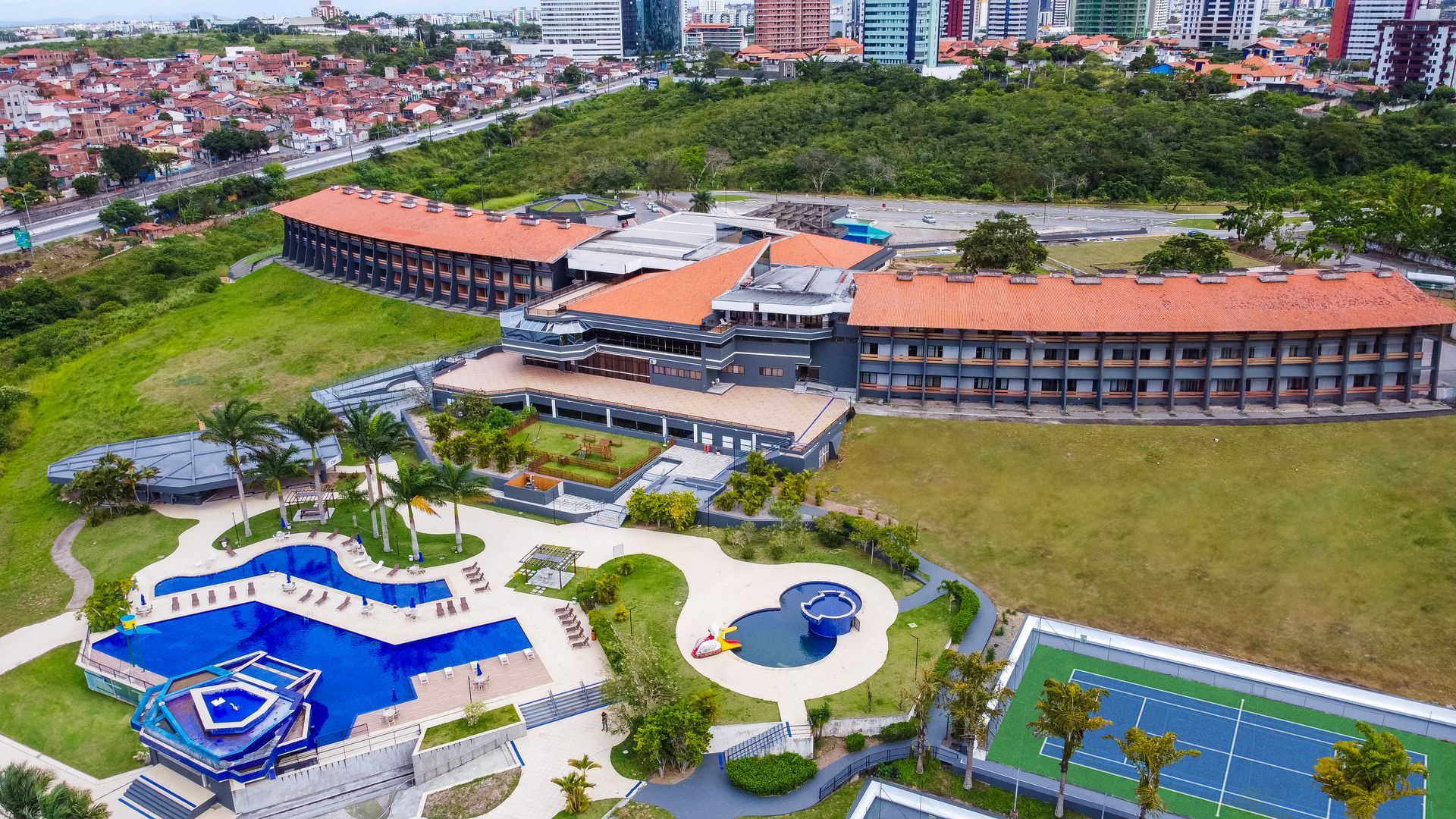 Uma vista aérea de um hotel com piscina e quadras de tênis.