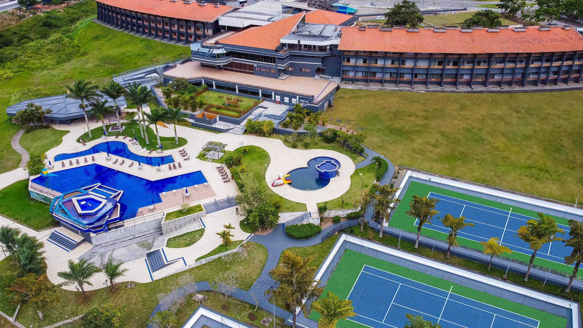 Uma vista aérea de um resort com piscina e quadras de tênis
