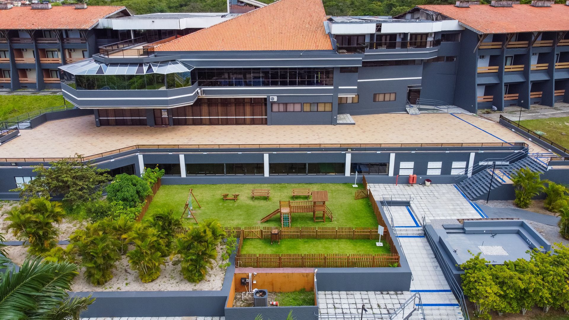 Uma vista aérea de um grande edifício com telhado de telhas vermelhas cercado por árvores.