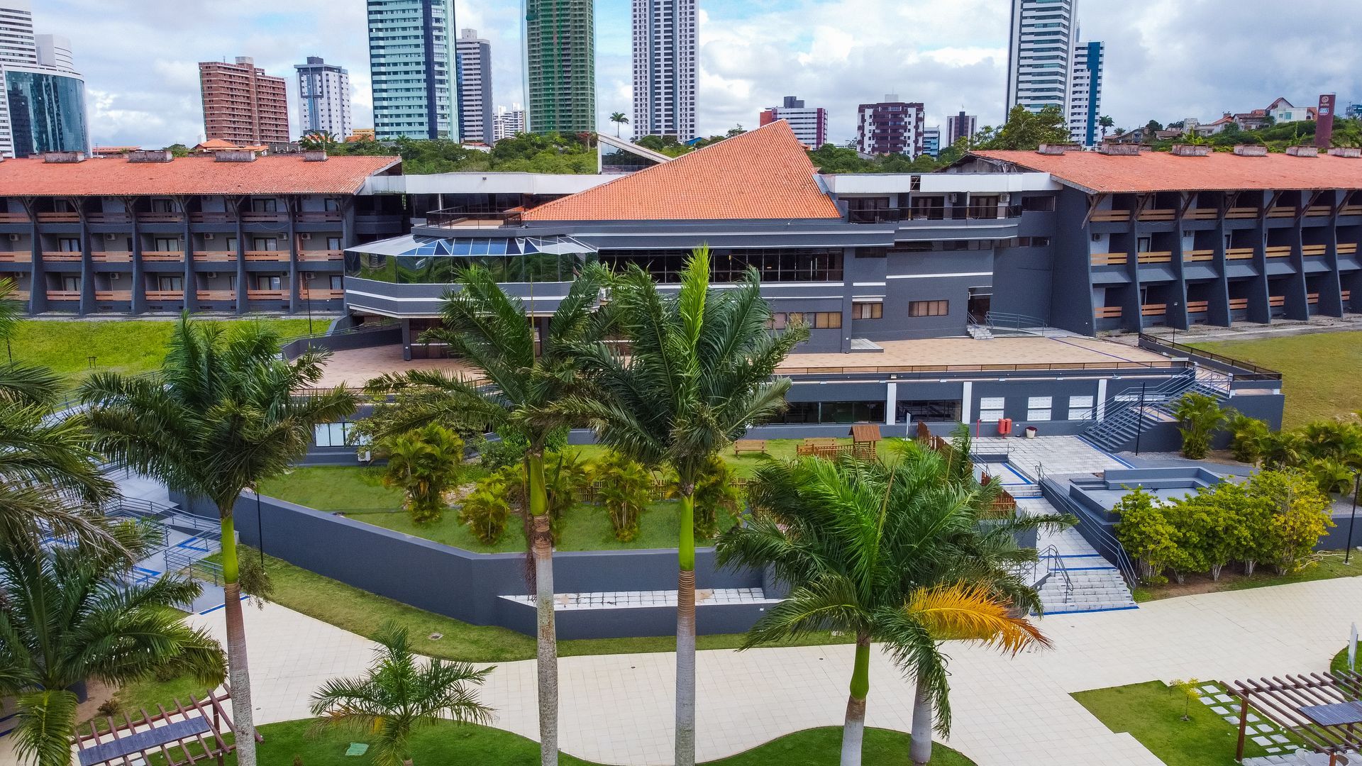 Uma vista aérea de um grande edifício com palmeiras na frente.