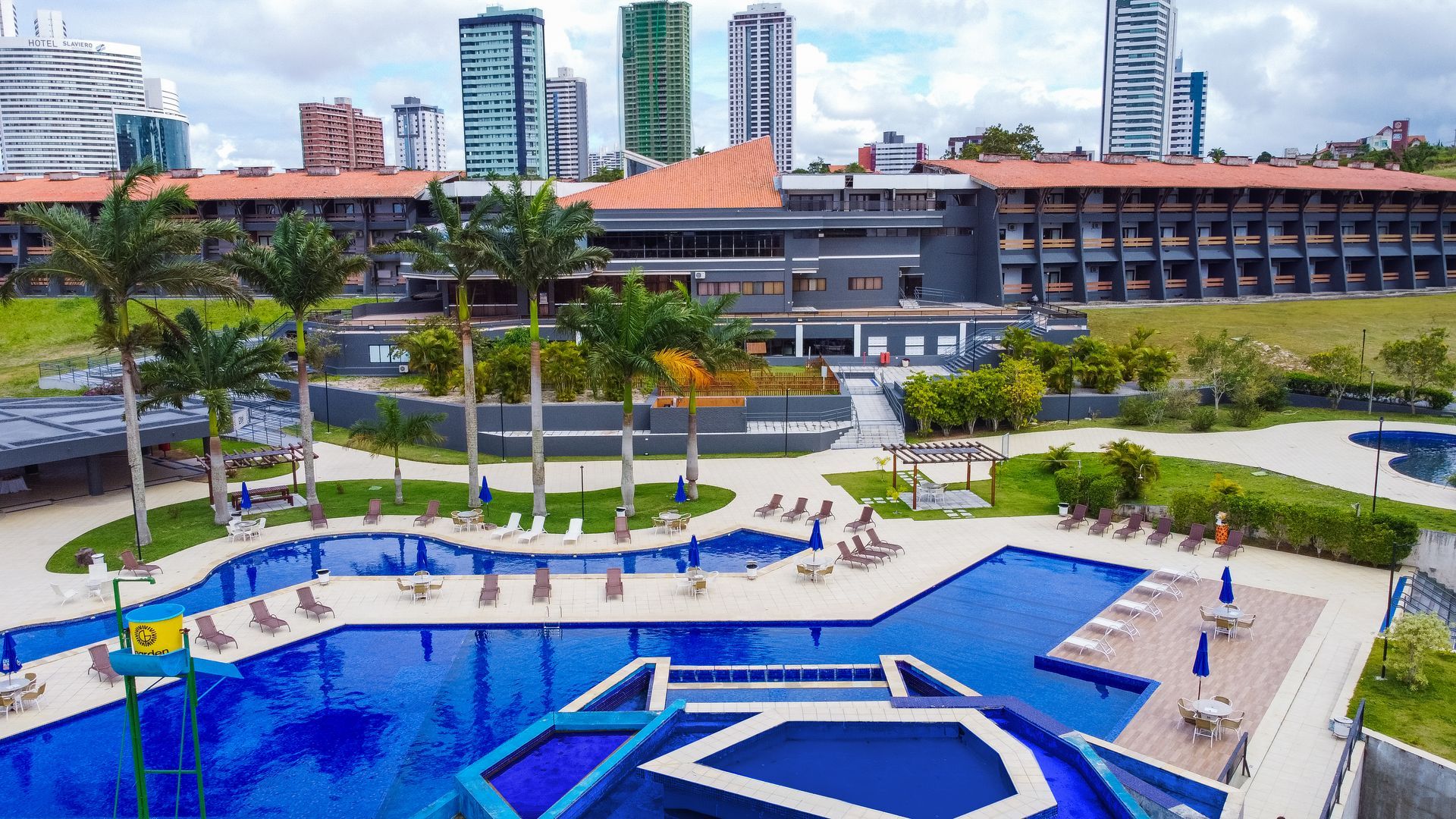 Uma vista aérea de uma grande piscina com um edifício ao fundo.