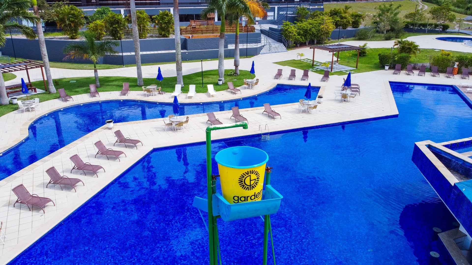 Uma vista aérea de uma grande piscina cercada por cadeiras e guarda-sóis.