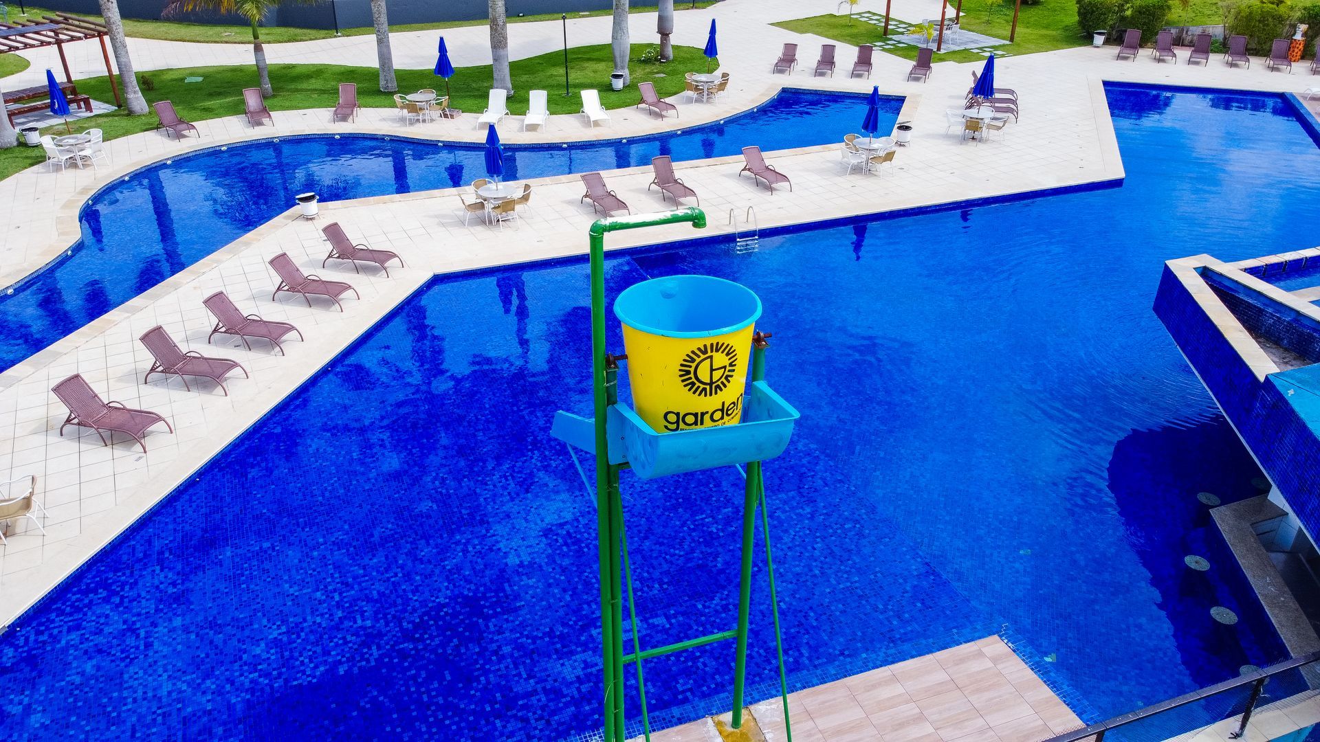 Uma vista aérea de uma grande piscina com uma torre de salva-vidas em primeiro plano.