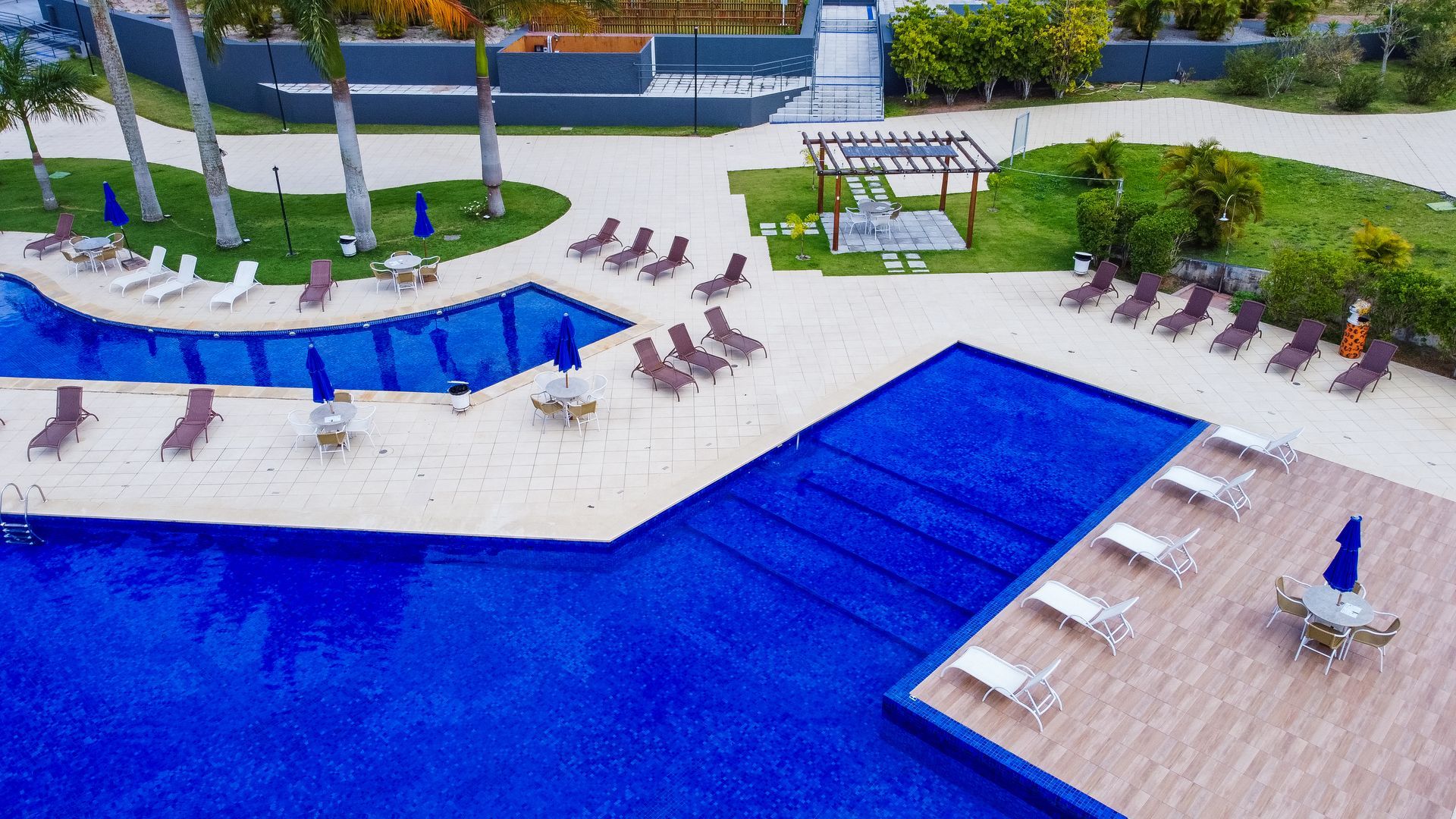 Uma vista aérea de uma grande piscina cercada por cadeiras e guarda-sóis.