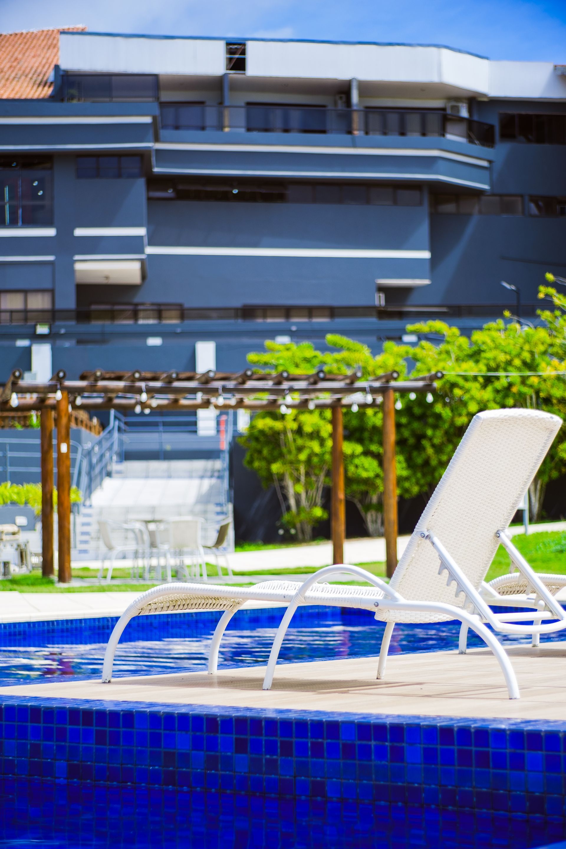 Uma piscina com cadeiras e um prédio ao fundo