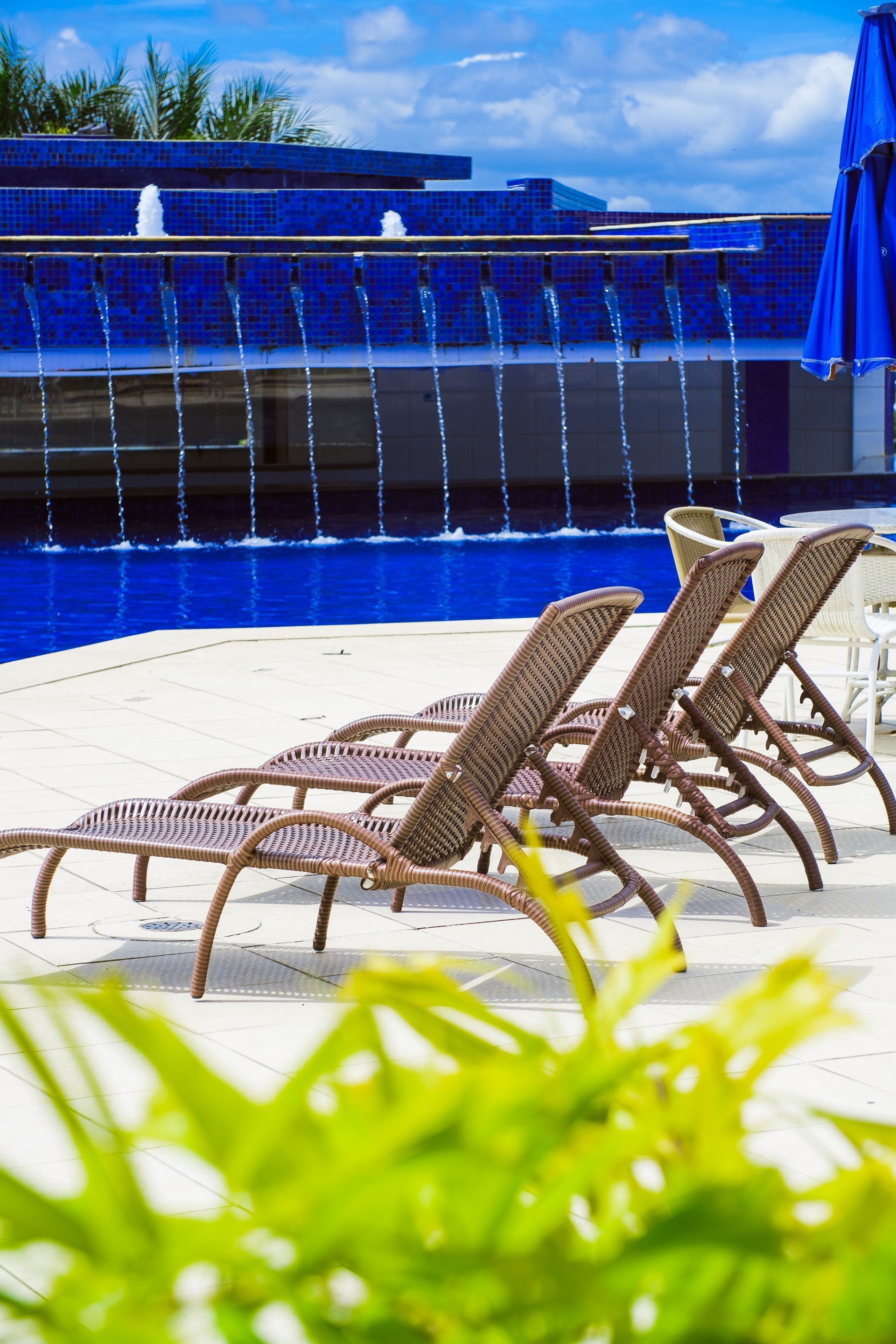 Uma fileira de espreguiçadeiras ao lado de uma piscina com uma cachoeira ao fundo