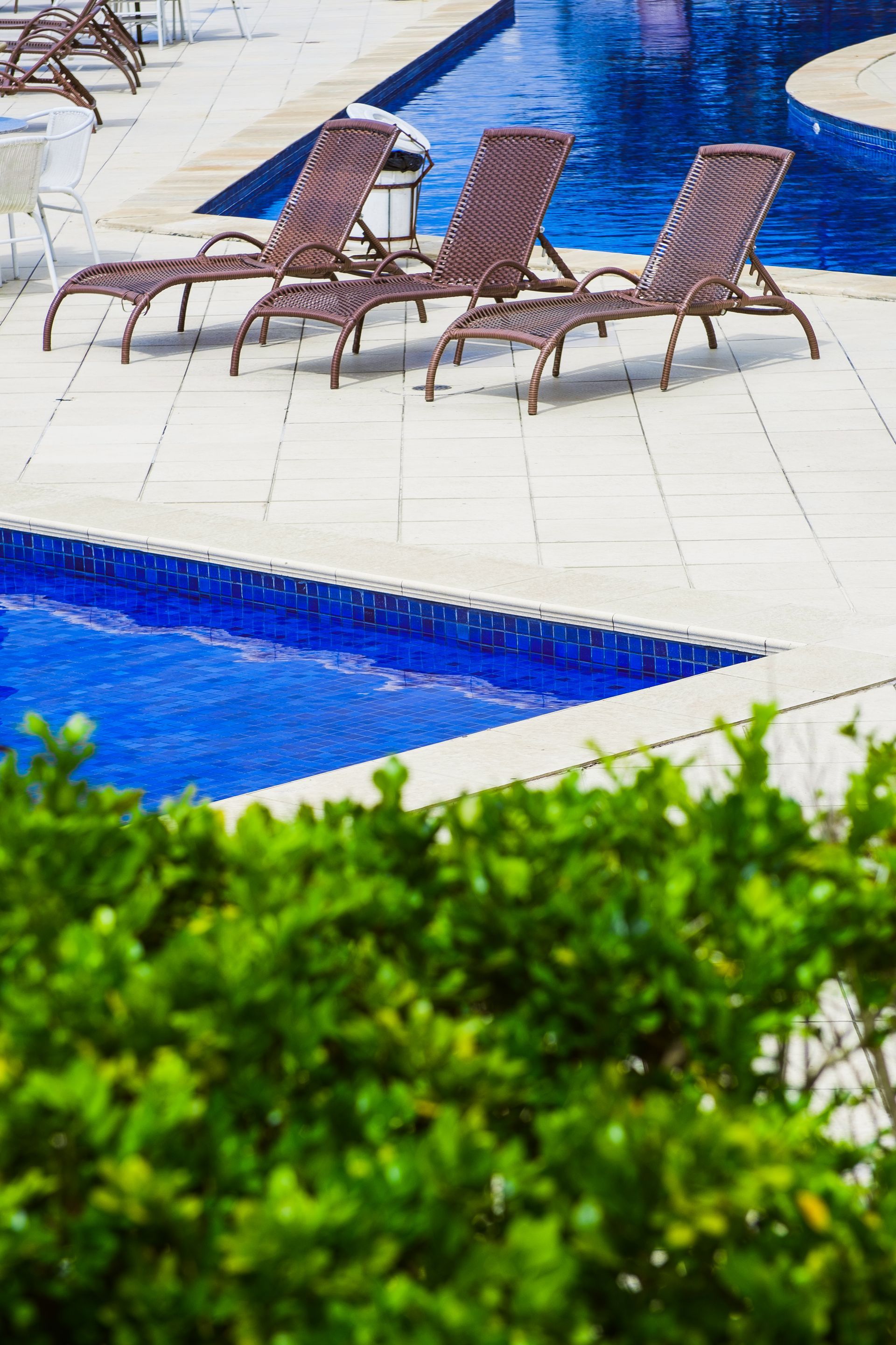 Uma fileira de espreguiçadeiras ao lado de uma piscina