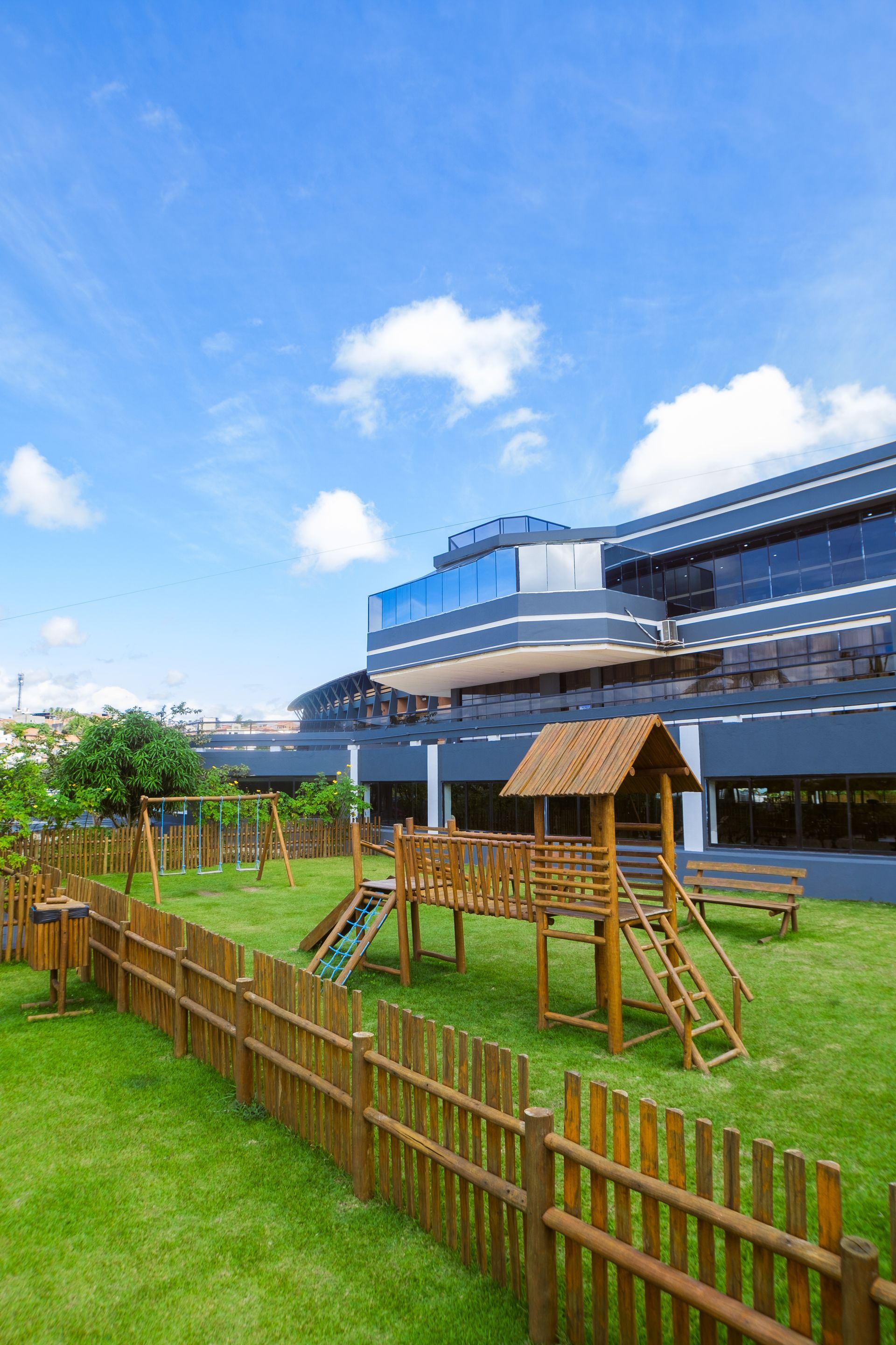 Um playground com uma cerca de madeira em frente a um grande edifício.
