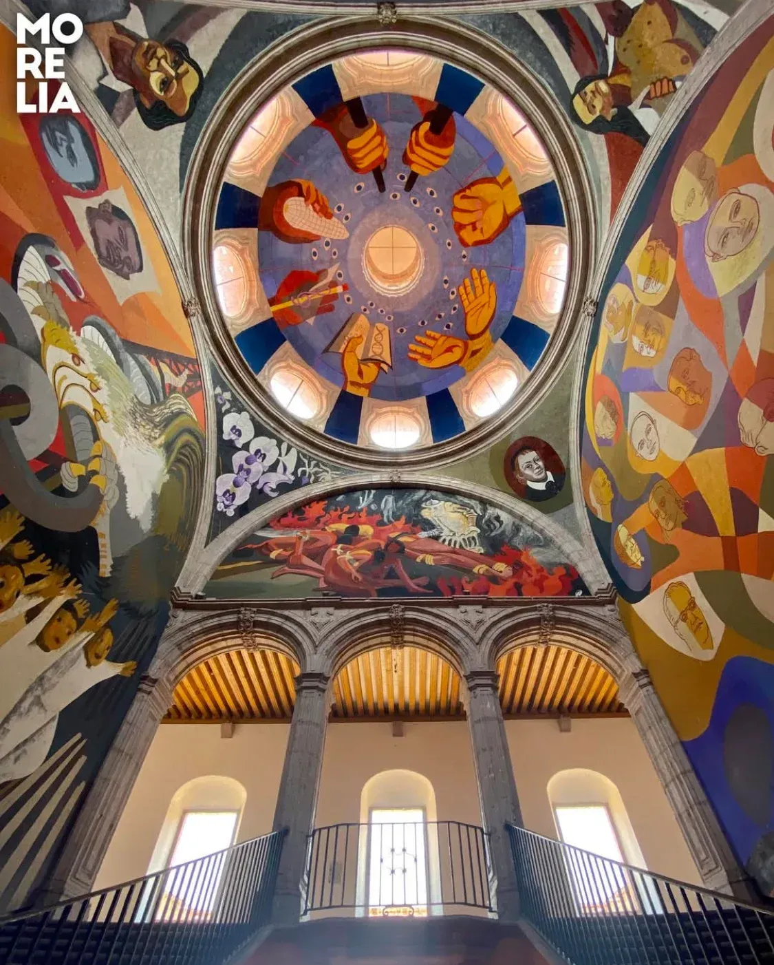 Looking up at the ceiling of a building with paintings on it