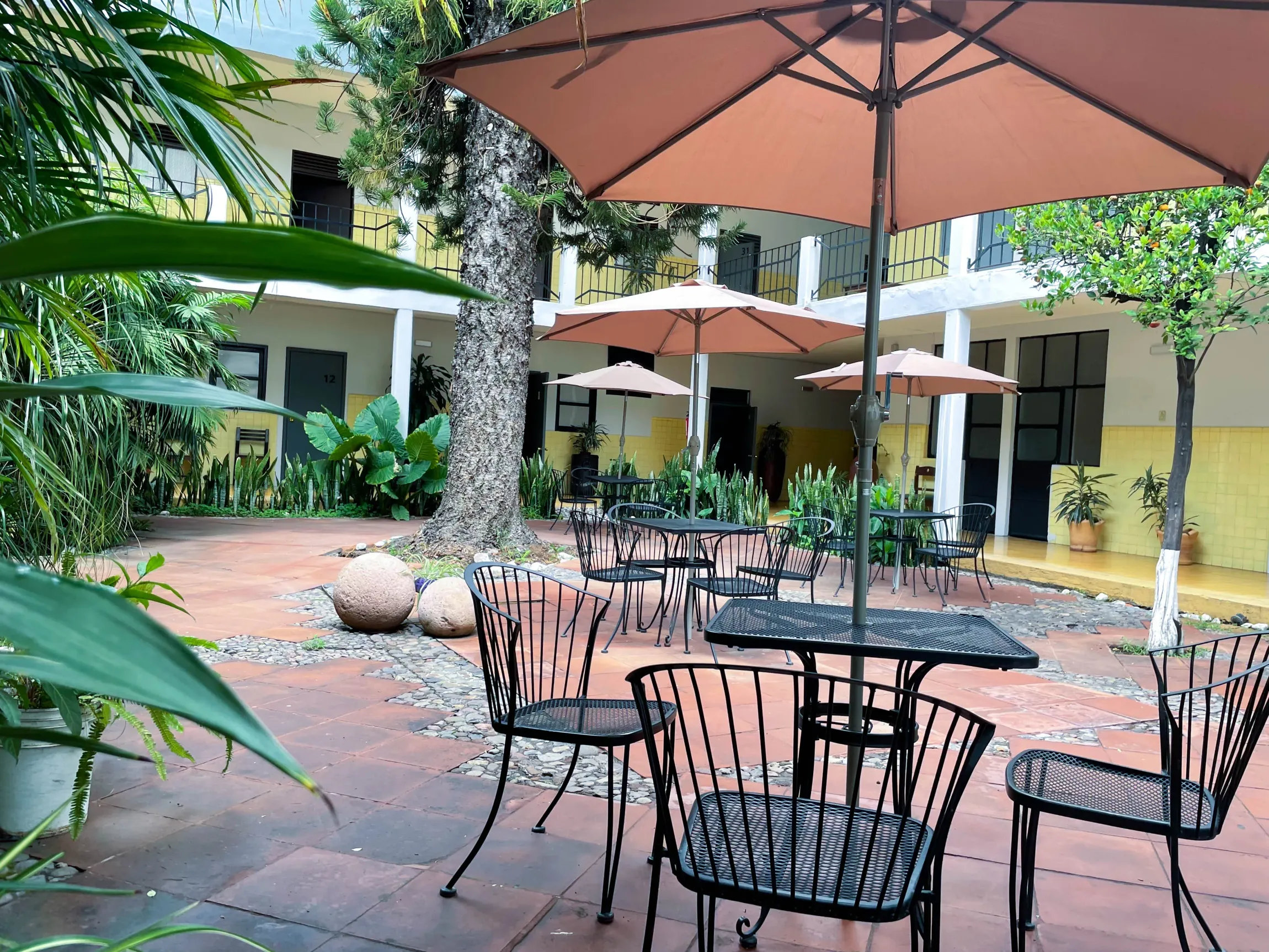 Un patio con mesas y sillas bajo sombrillas.