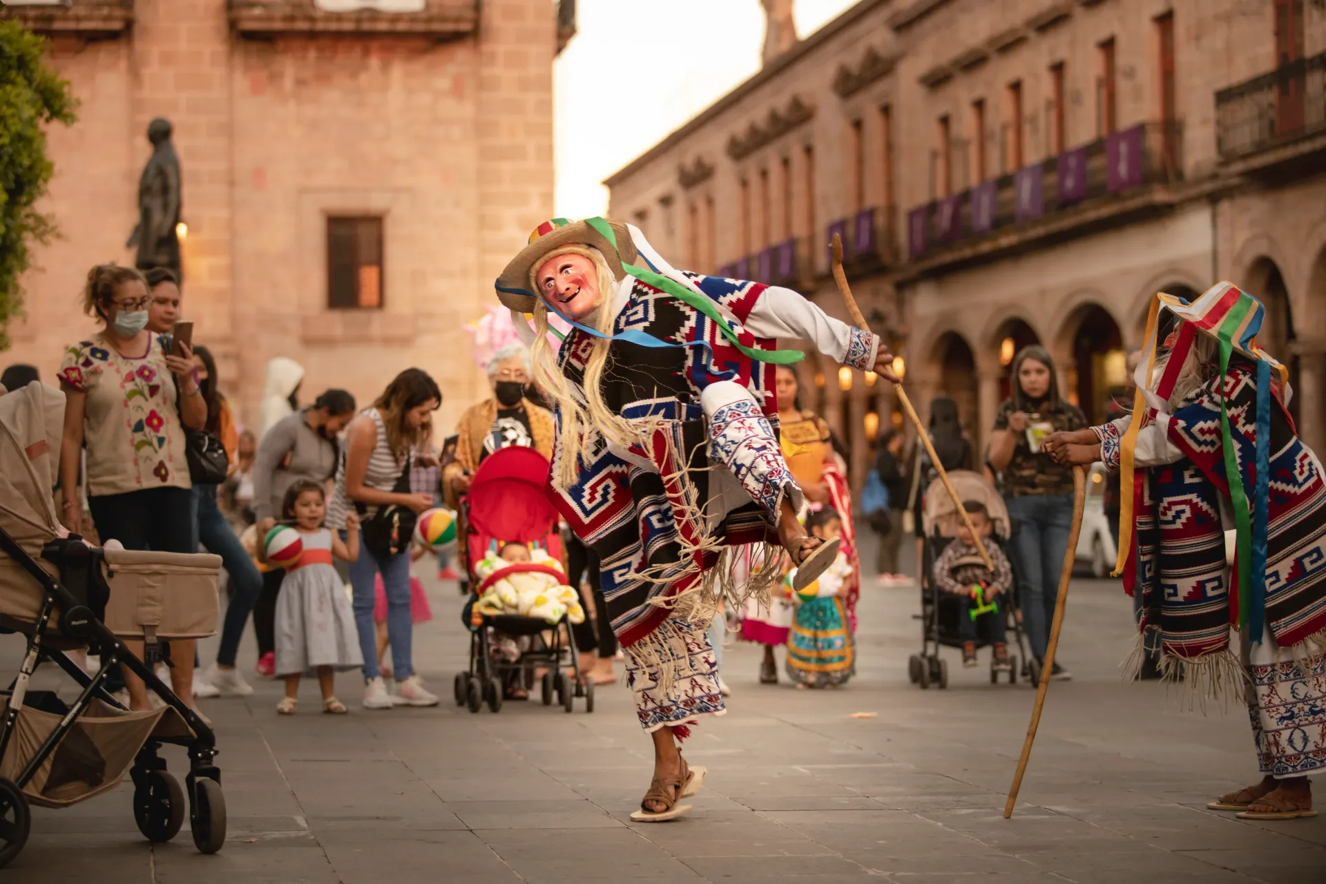 Un grupo de personas está bailando en una calle frente a un edificio.