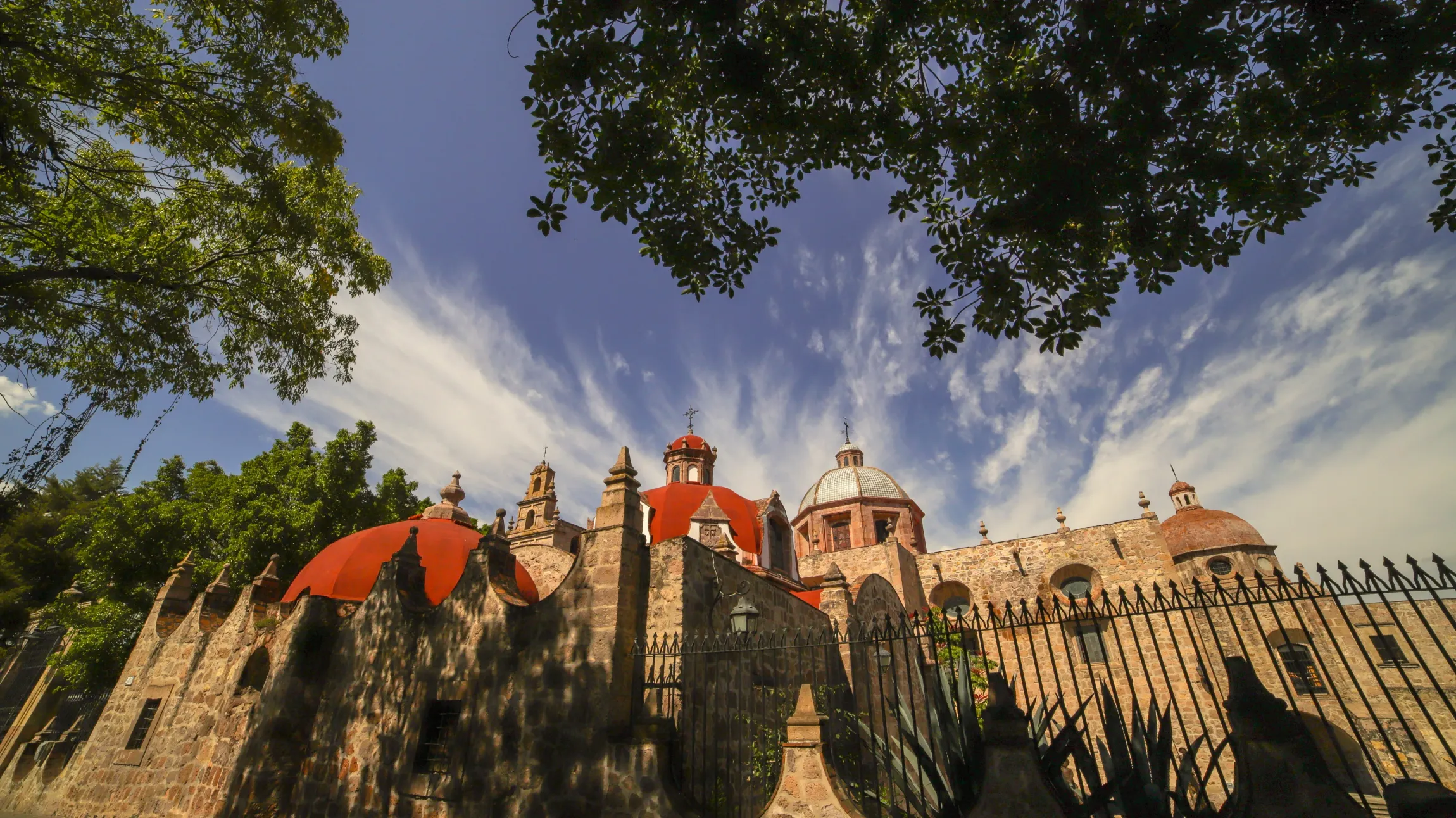 Un castillo con tejados rojos y una valla delante.