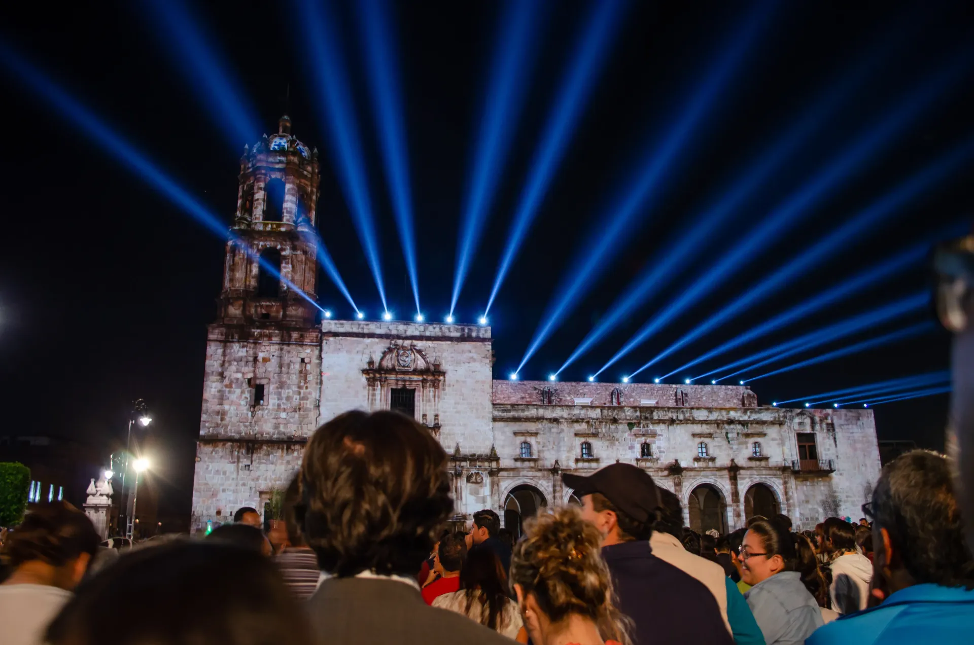 Una multitud de personas está mirando un espectáculo de luces frente a un edificio.