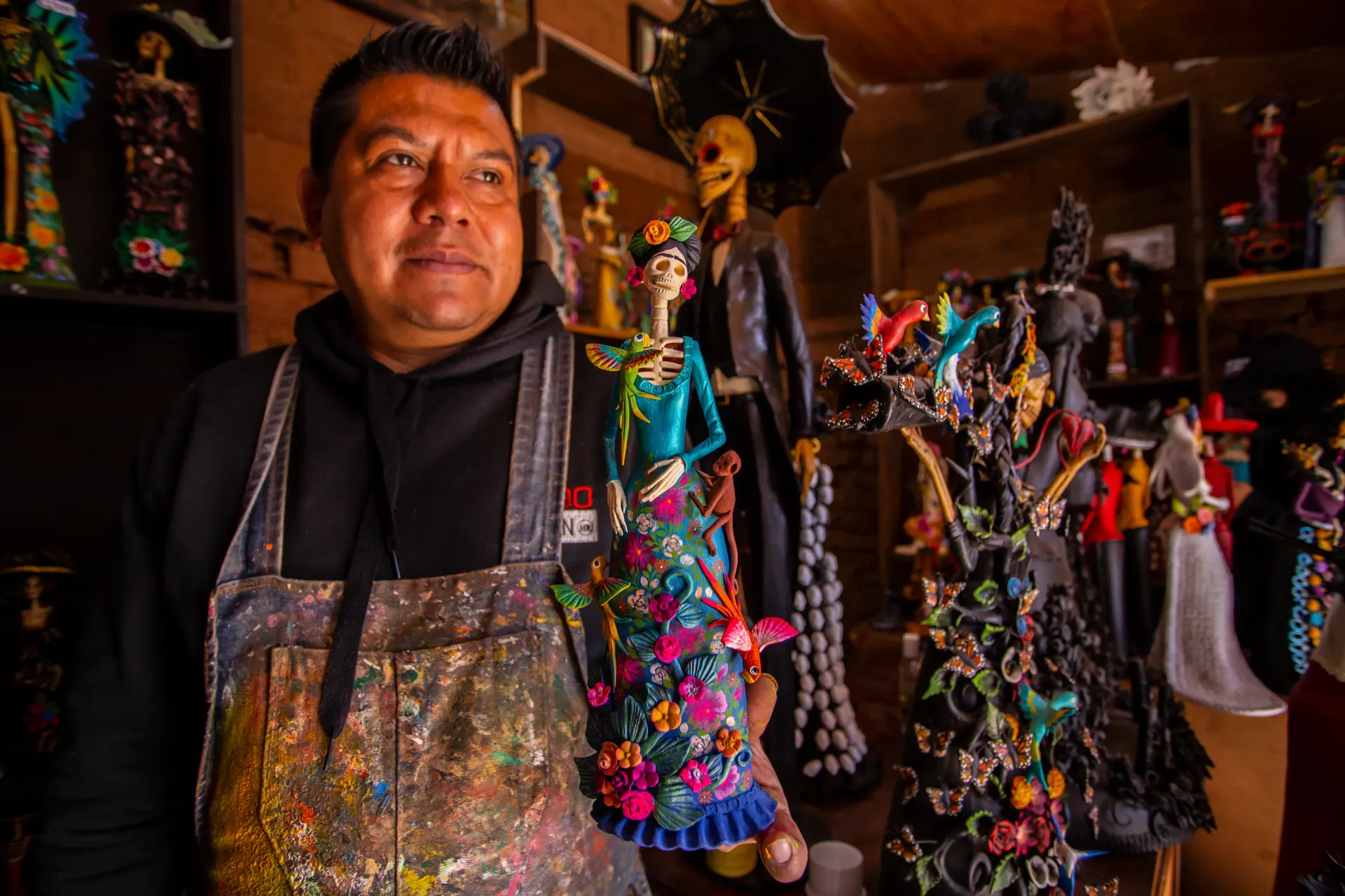 Un hombre con delantal sostiene una muñeca en una tienda.