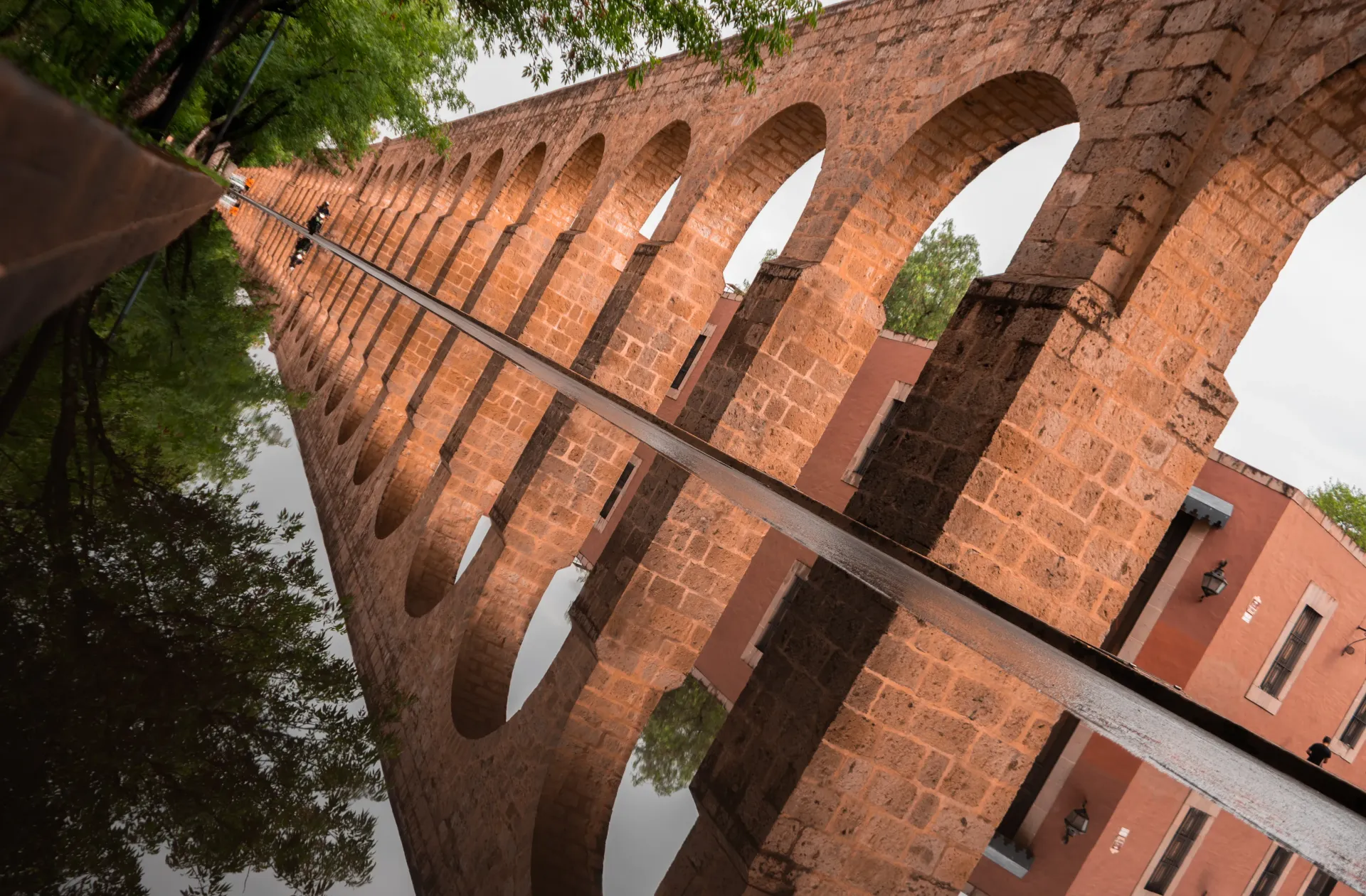 Un puente de ladrillo se refleja en un charco de agua.