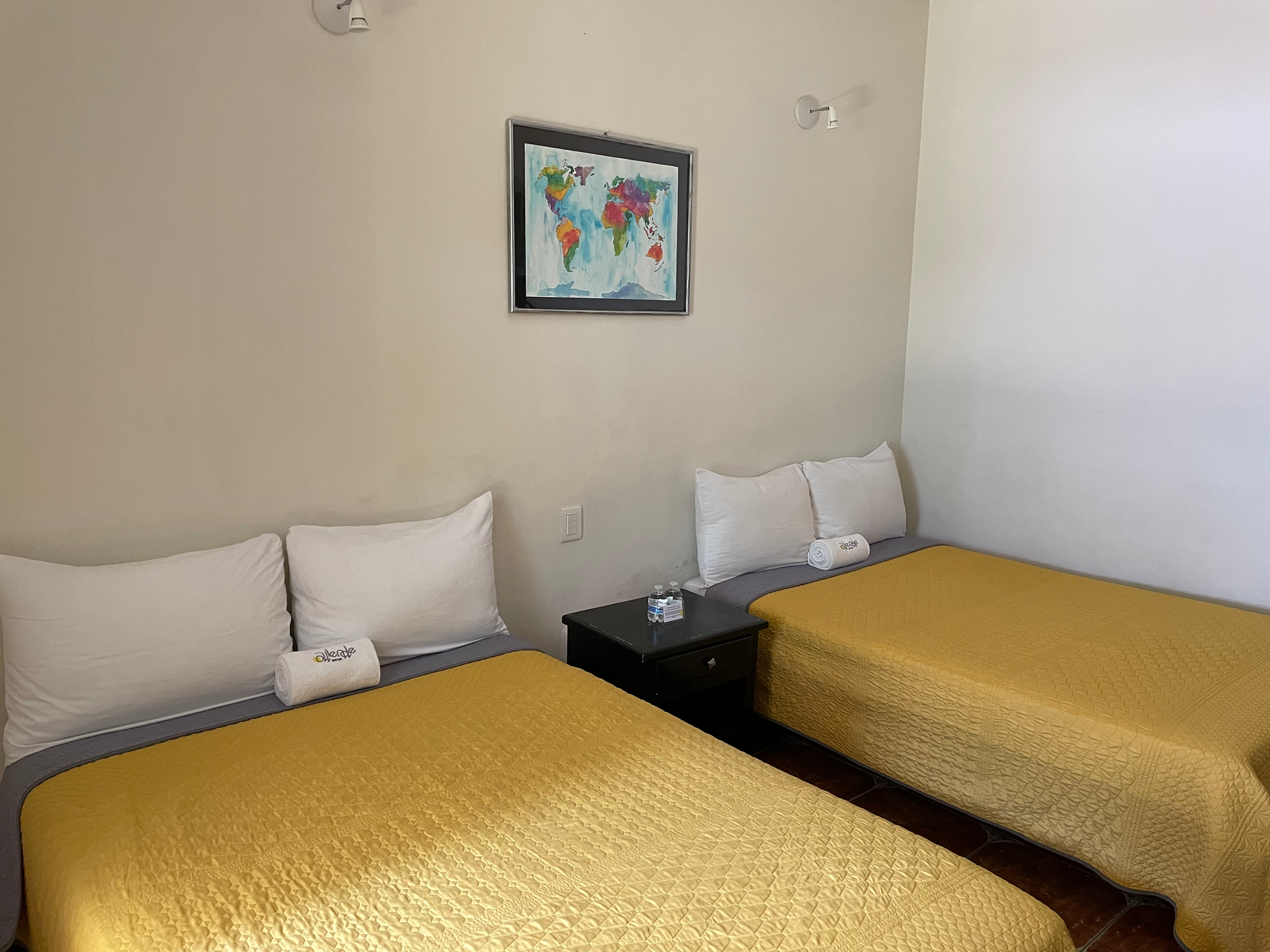 Una habitación de hotel con dos camas y un mapa del mundo en la pared.