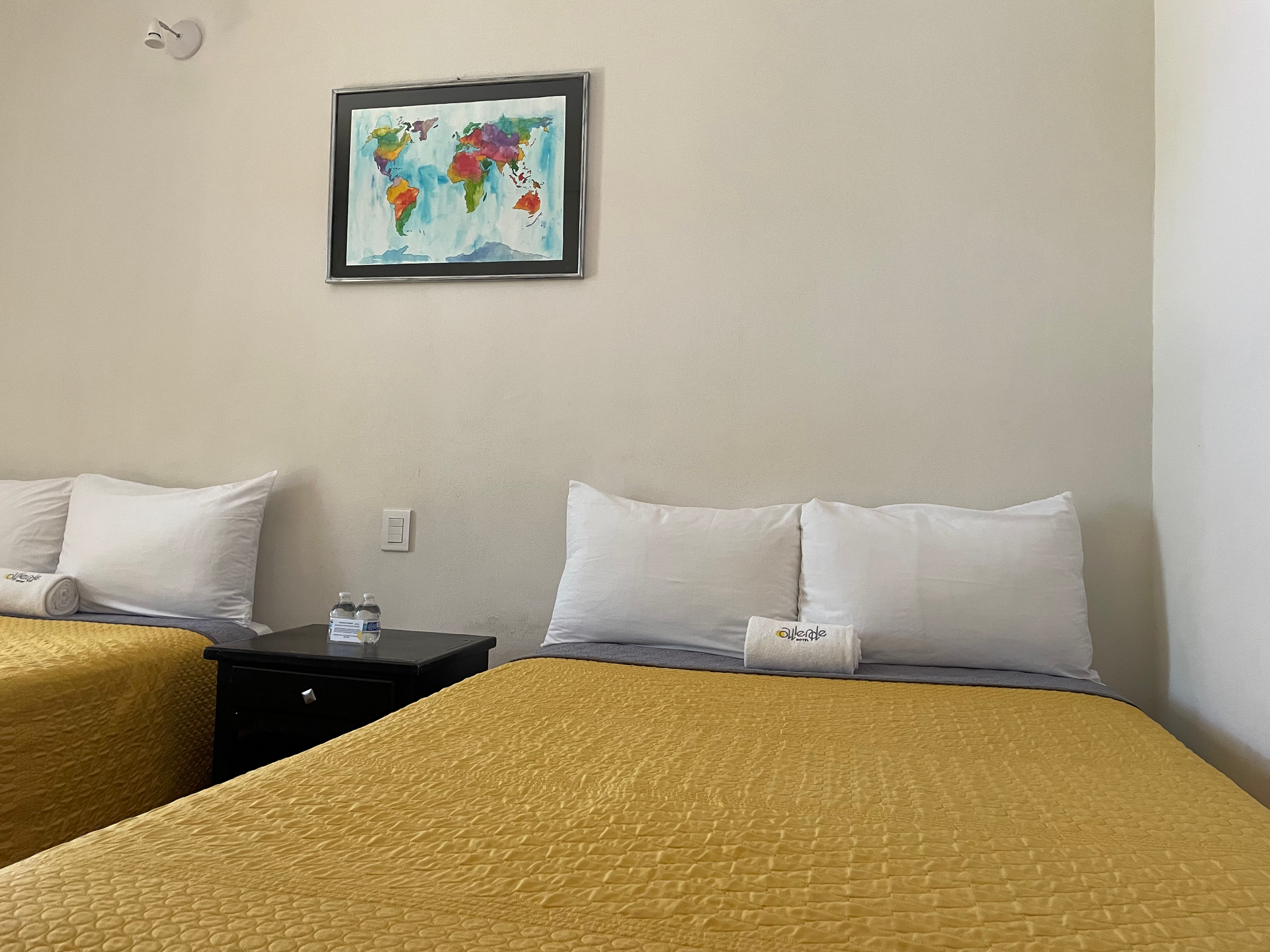 Una habitación de hotel con dos camas y un mapa del mundo en la pared.