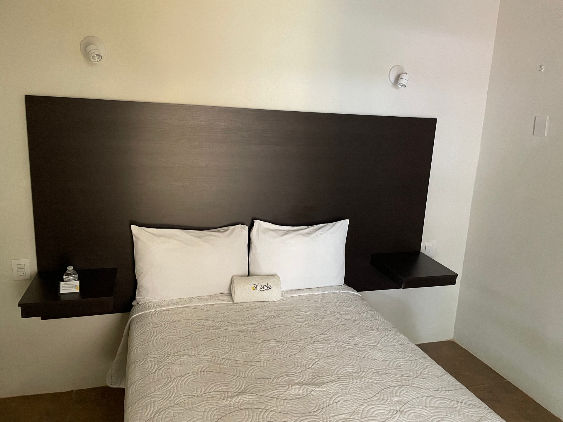 A hotel room with a bed and a wooden headboard.
