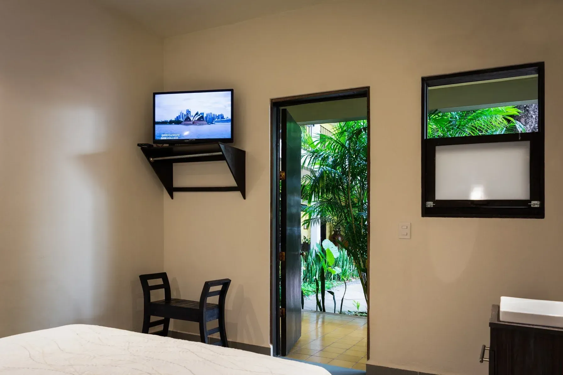 A bedroom with a bed and a television on the wall.