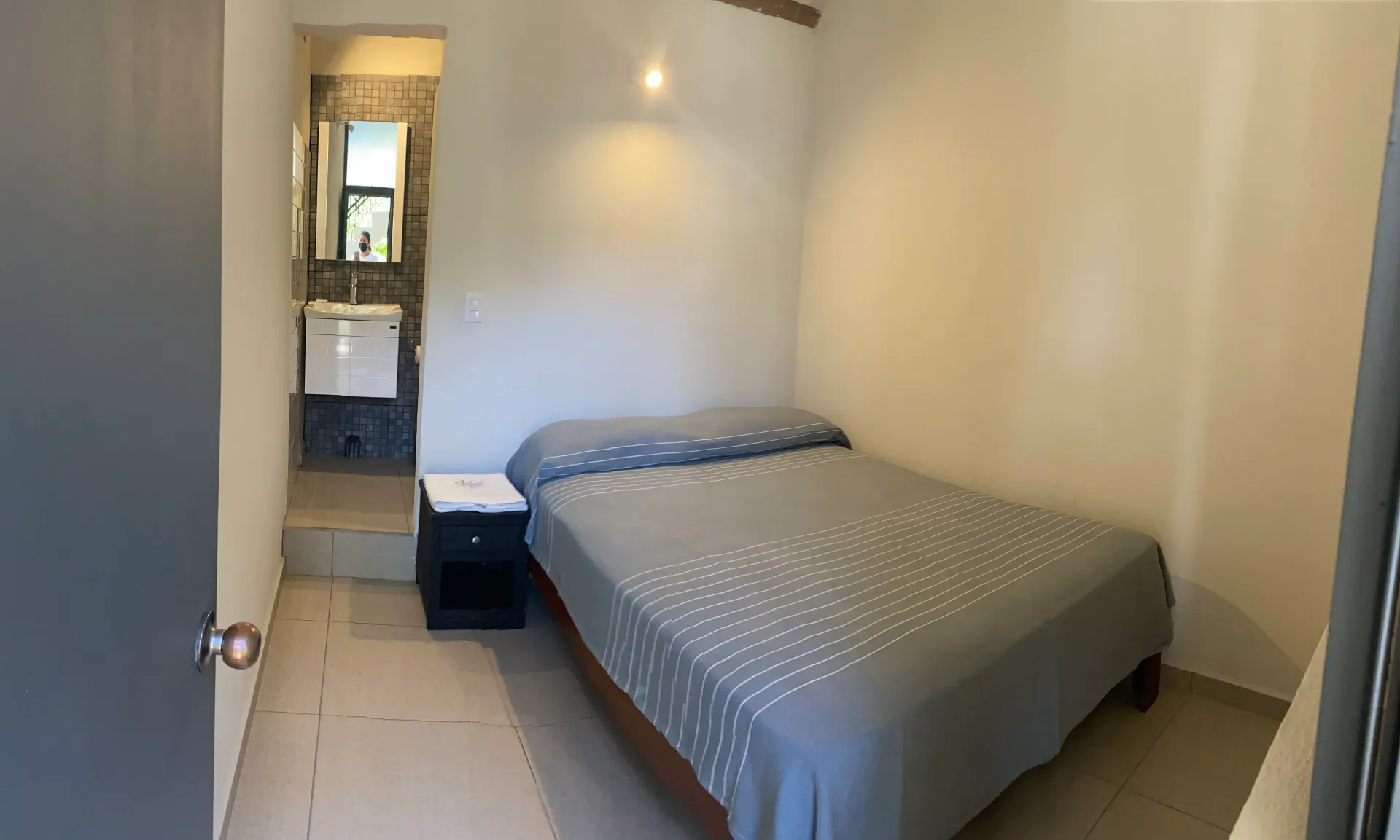 A bedroom with a bed , nightstand , and bathroom.