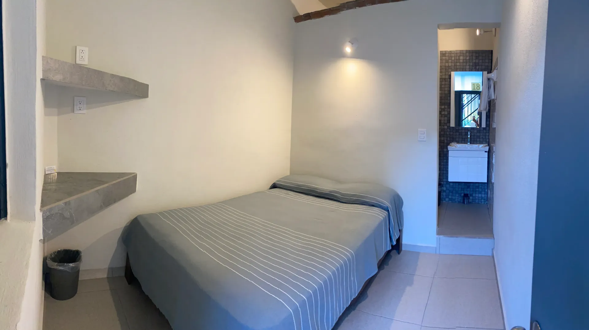 A bedroom with a bed and a bathroom in the background.
